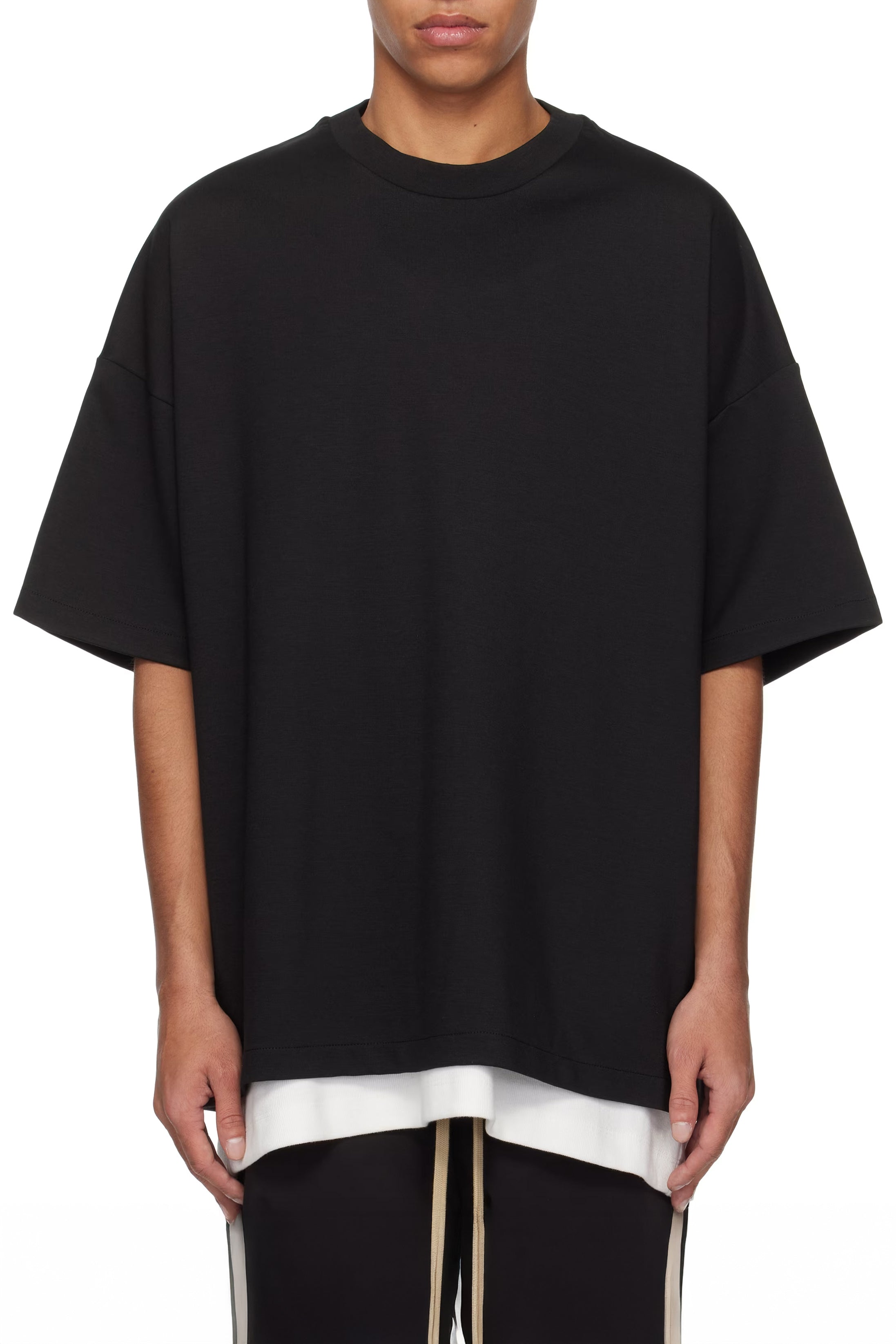 Person wearing a black oversized t-shirt with a white shirt underneath on a white background
