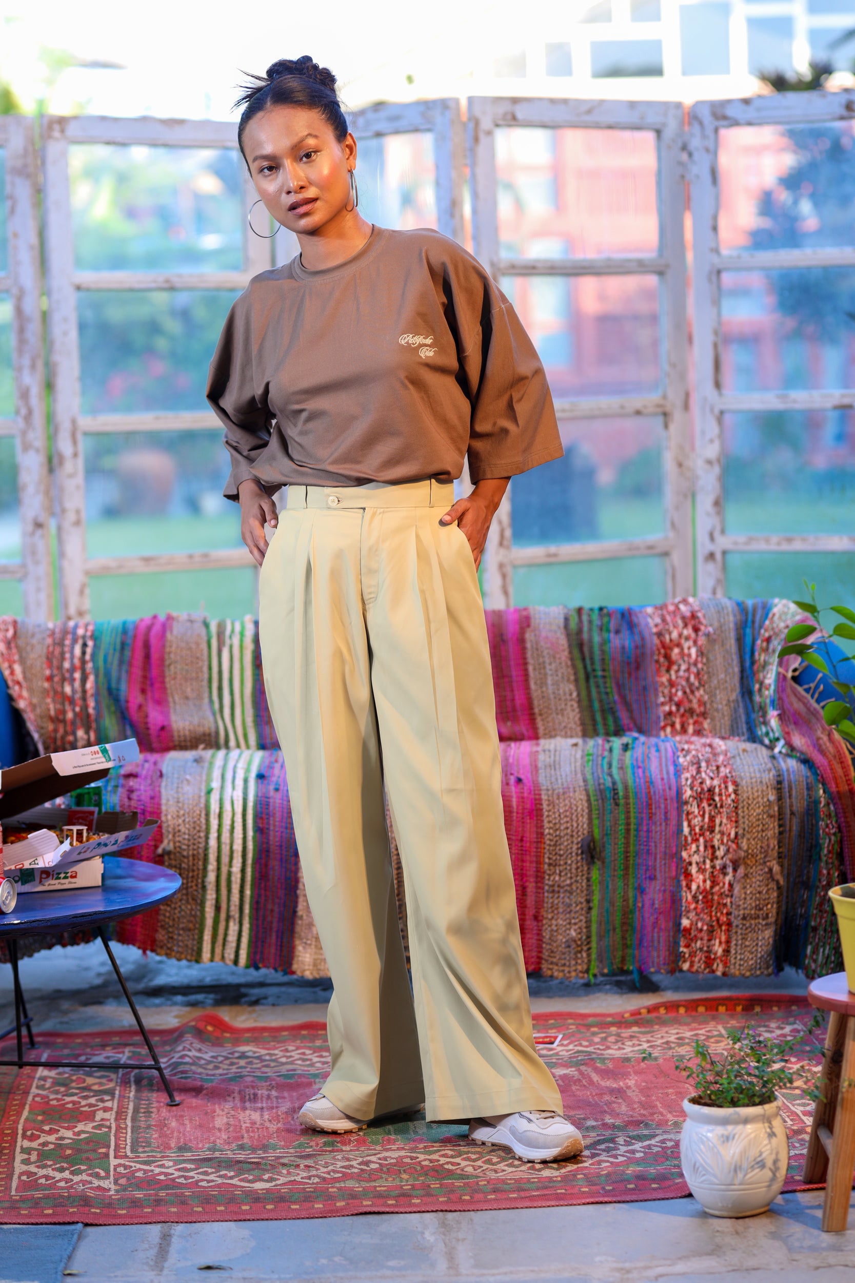 Person wearing a brown shirt and beige pants standing in a room with colorful furniture and decor.