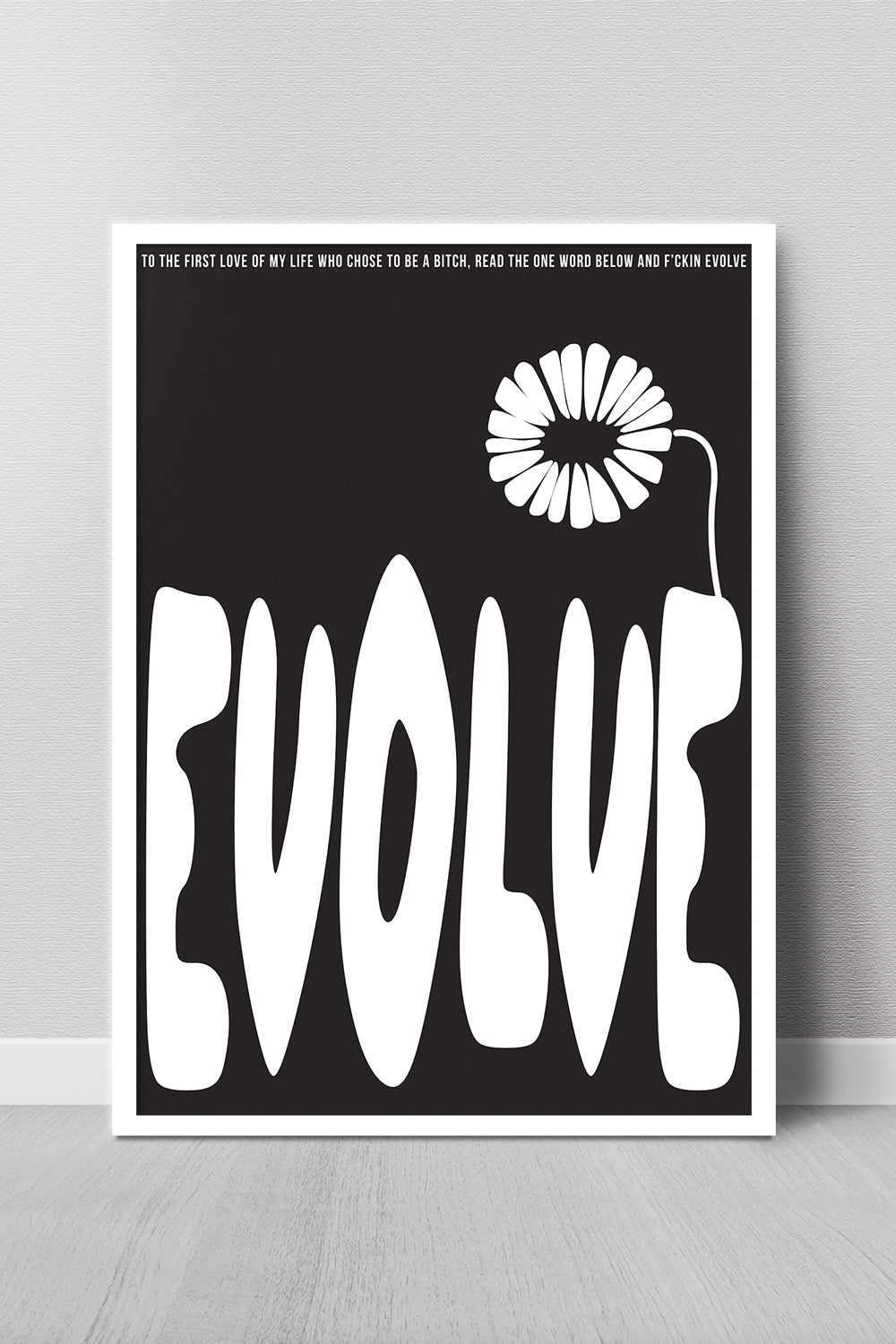 Poster with the word 'EVOLVE' and a flower design on a black background, leaning against a gray wall.