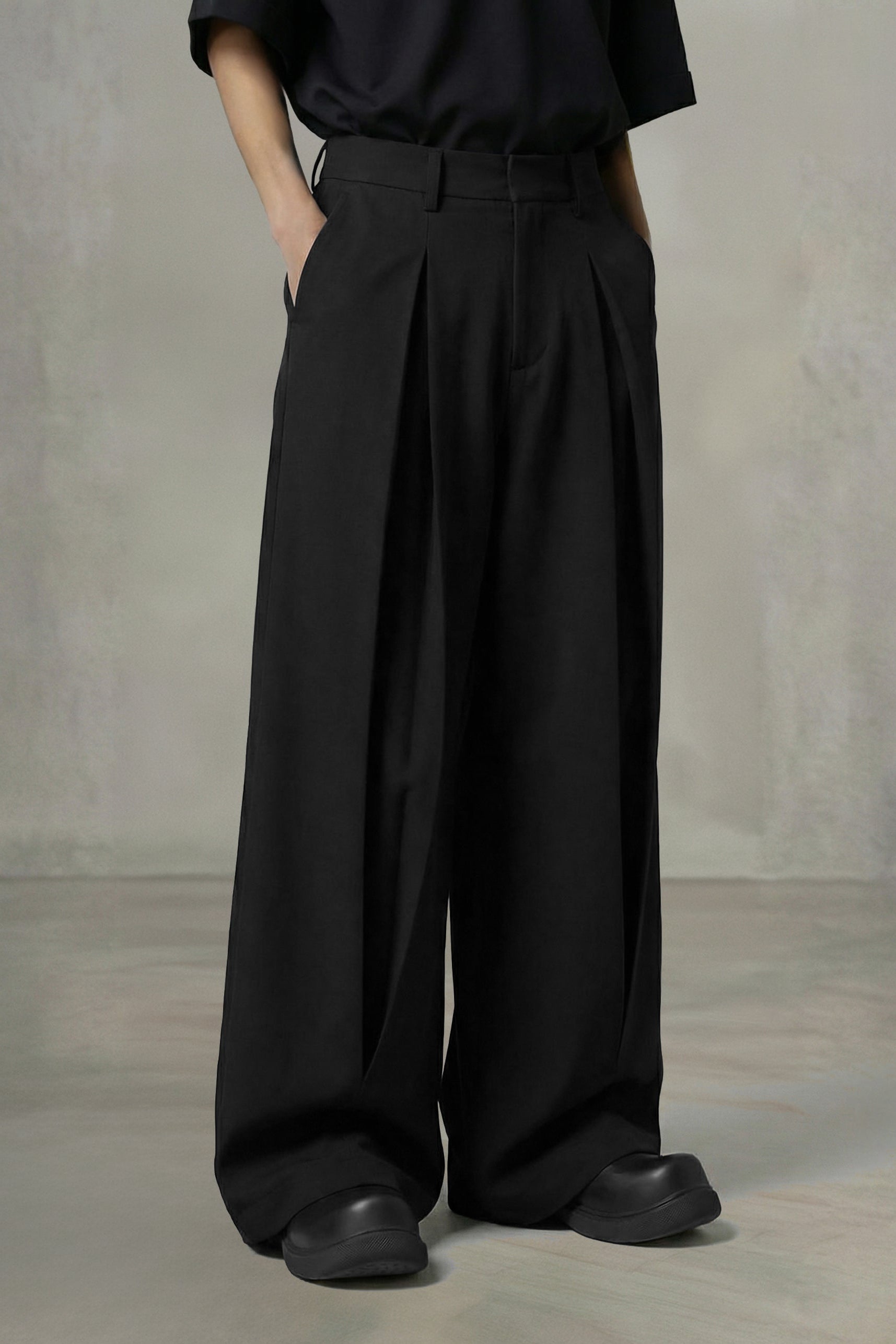 Person wearing black wide-leg pants and a black shirt against a plain background