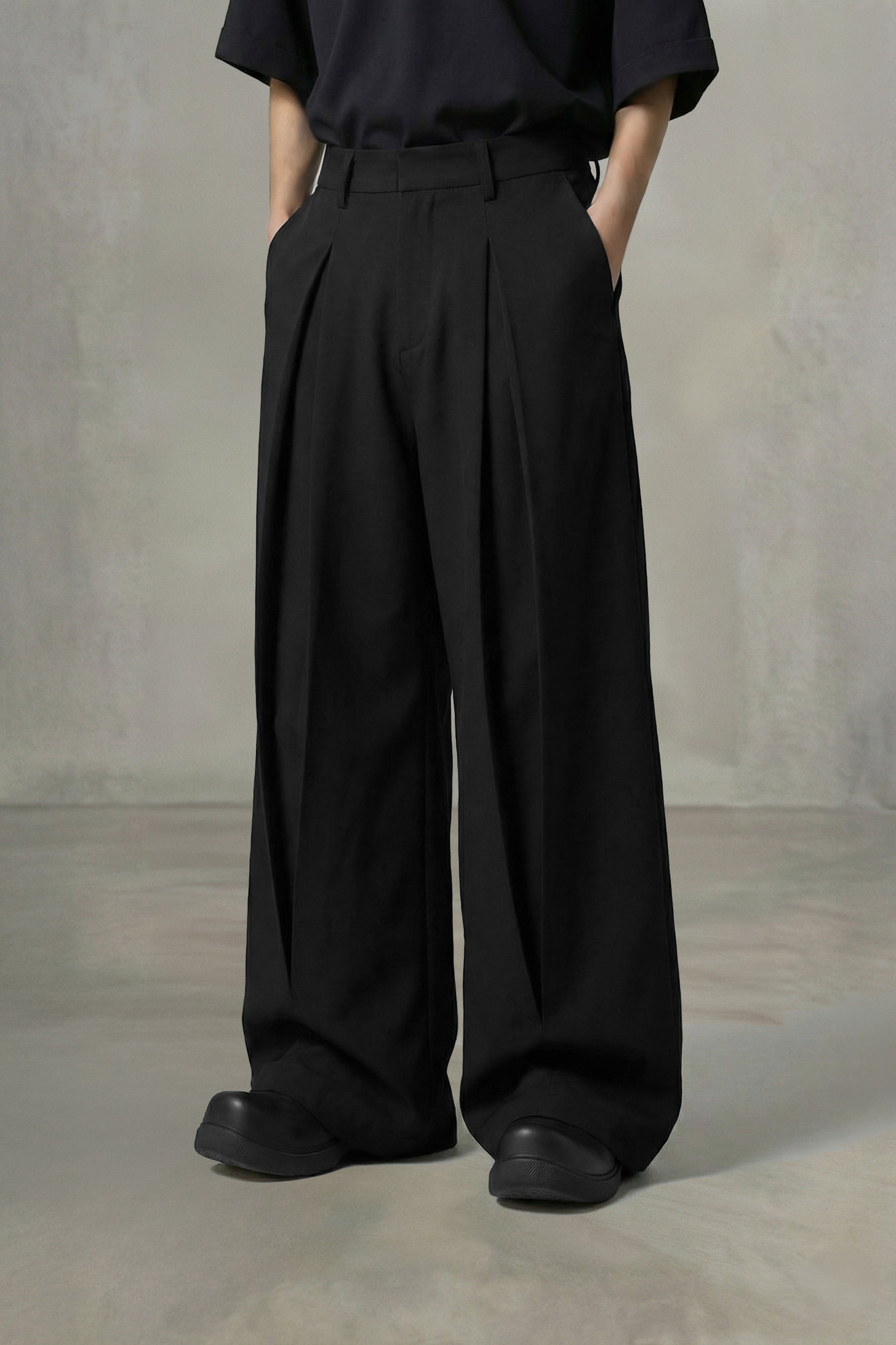 Person wearing black wide-leg pants and a black shirt against a plain background