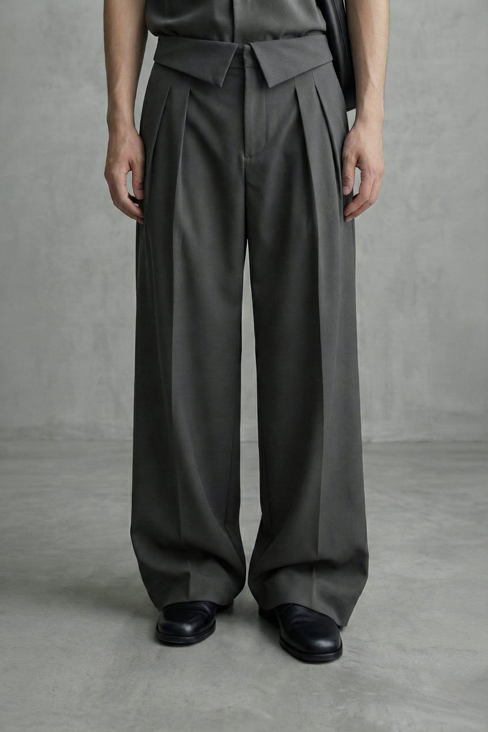 Person wearing dark gray wide-leg pants and a matching top against a plain background