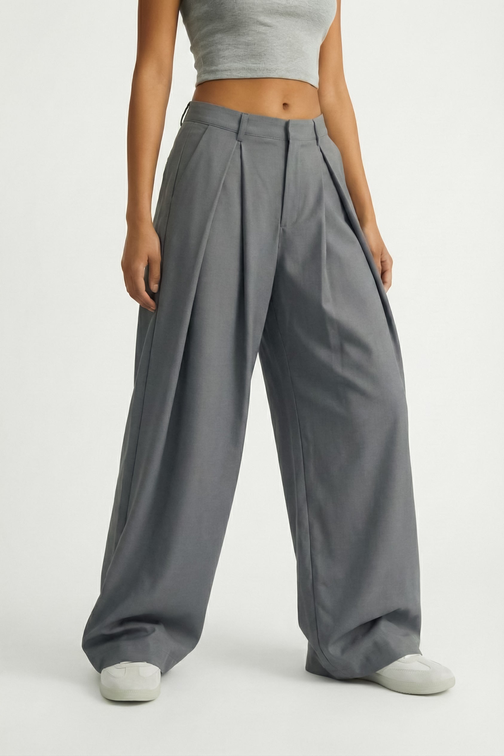 Person wearing gray wide-leg pants and a cropped top on a plain background