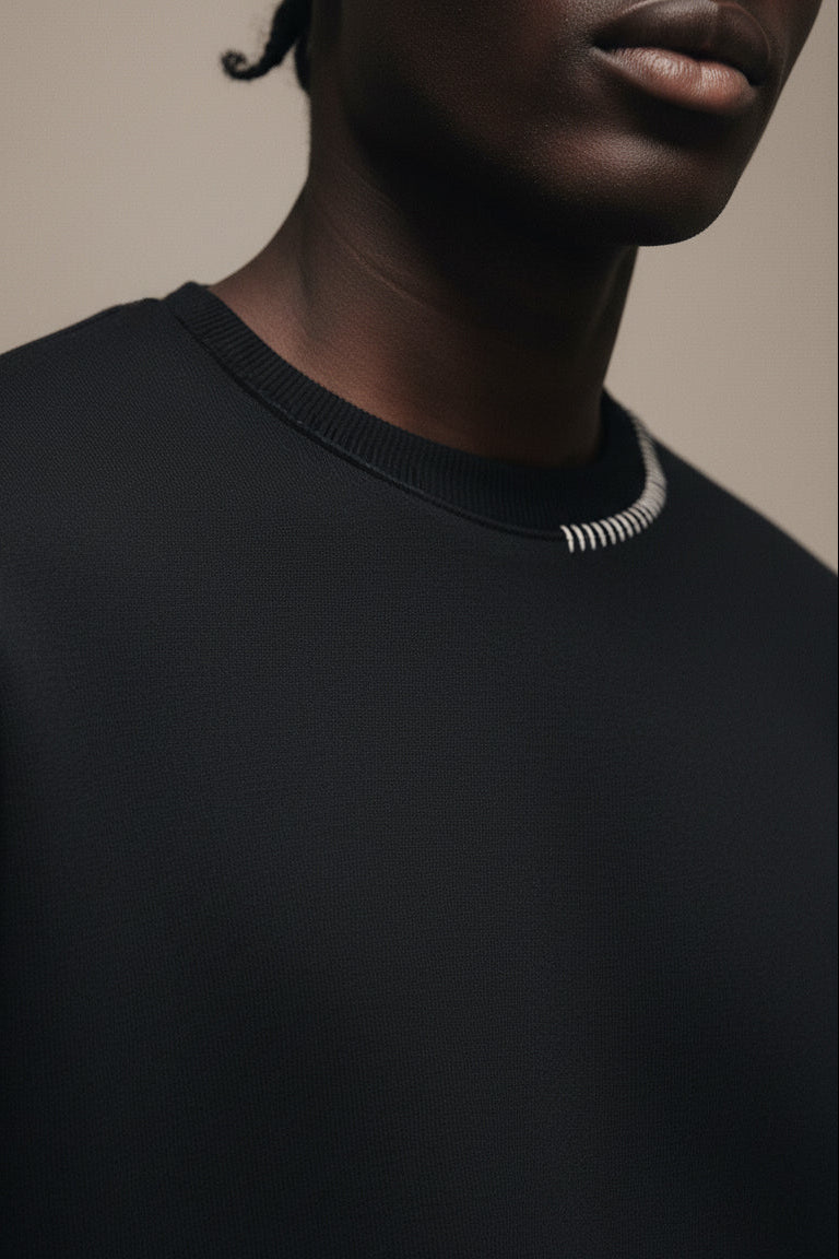 Person wearing a black sweater with a neutral background