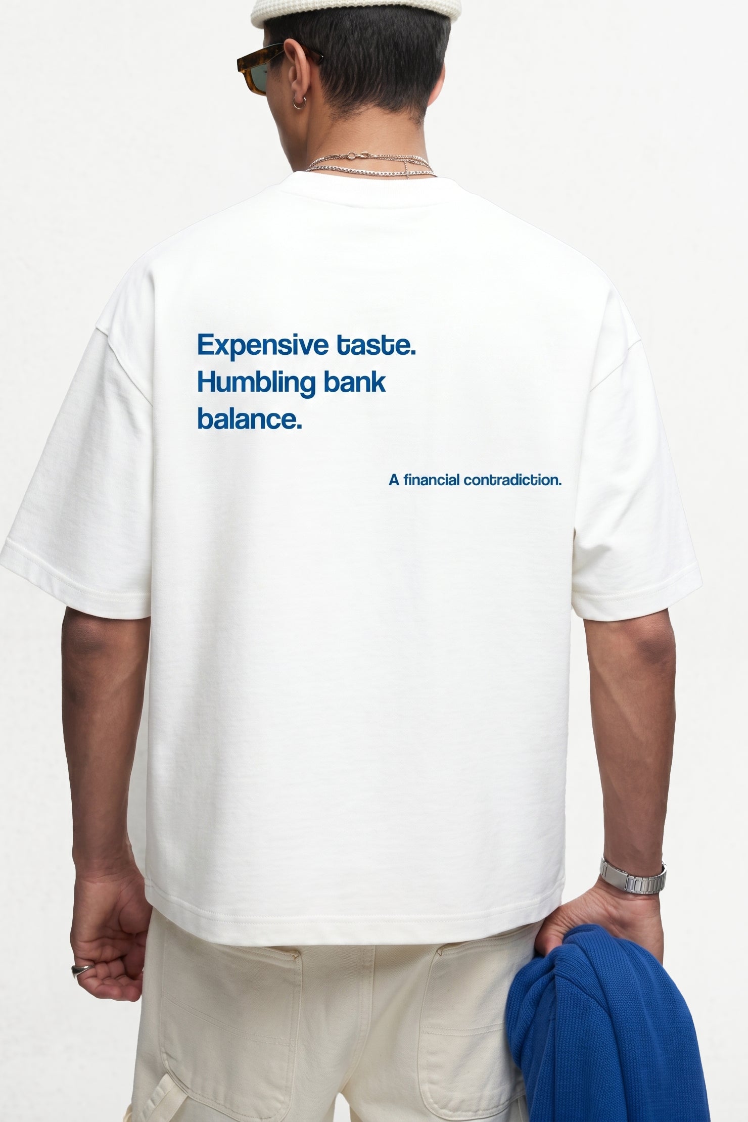 Person wearing a white t-shirt with text on the back, standing against a plain background.