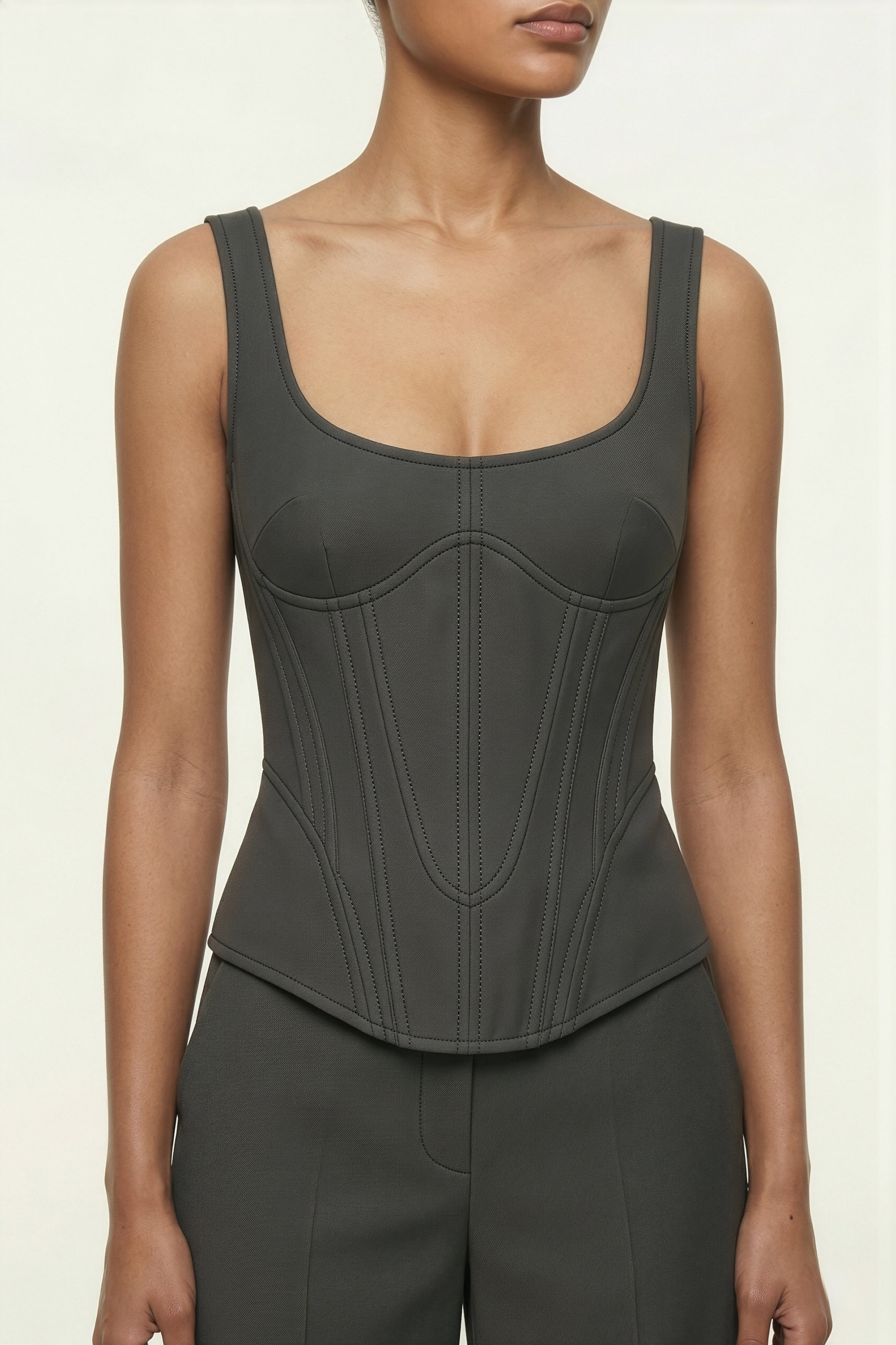 Person wearing a black corset-style top on a beige background