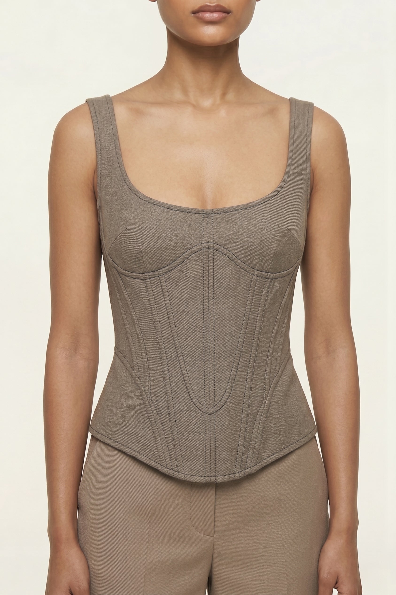 Woman wearing a brown corset top against a plain background