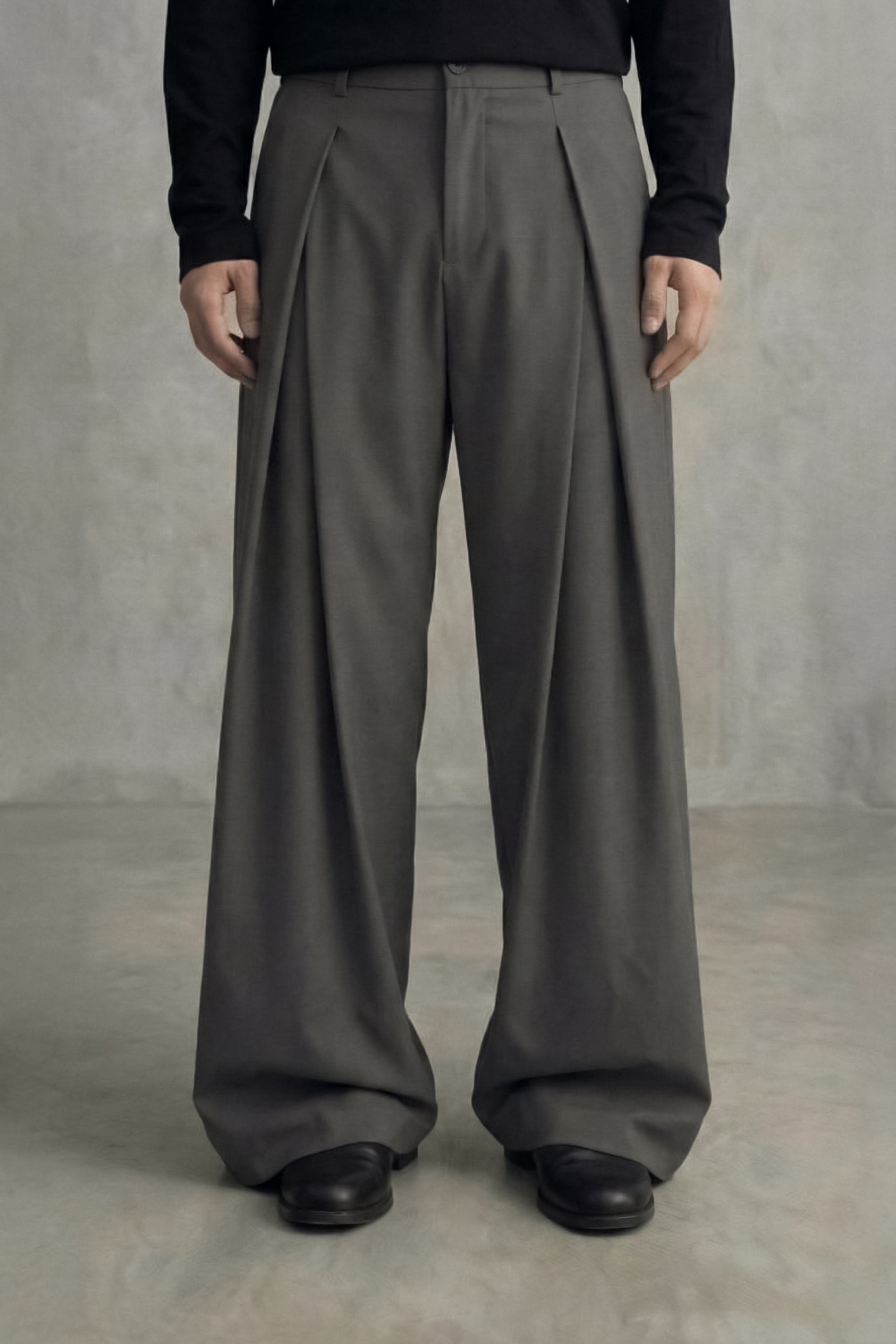 Person wearing gray wide-leg pants and black shoes against a neutral background