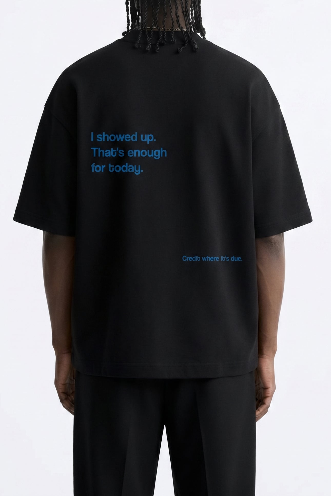 Person wearing a black t-shirt with blue text on the back against a white background