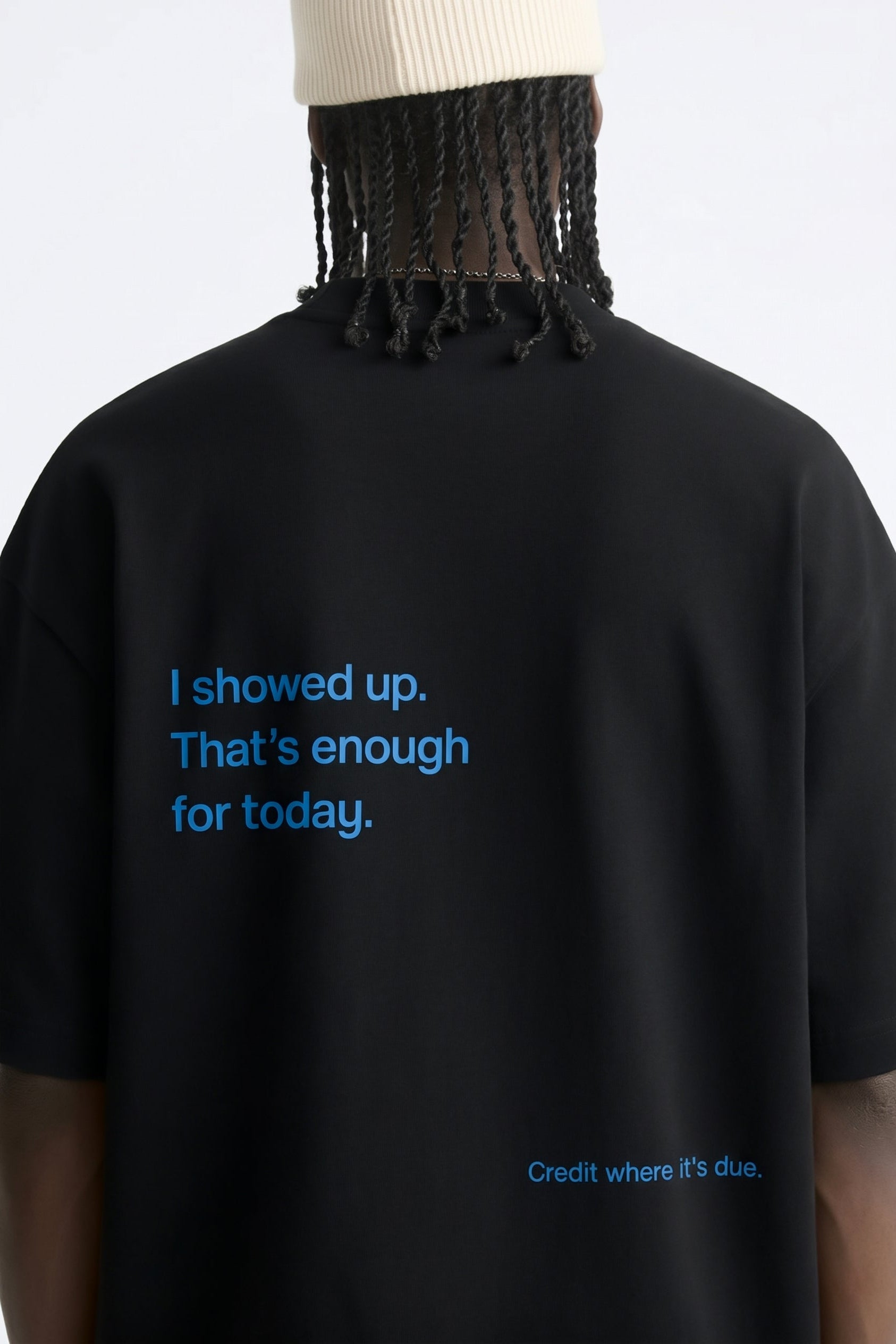 Black t-shirt with blue text on the back, worn by a person.
