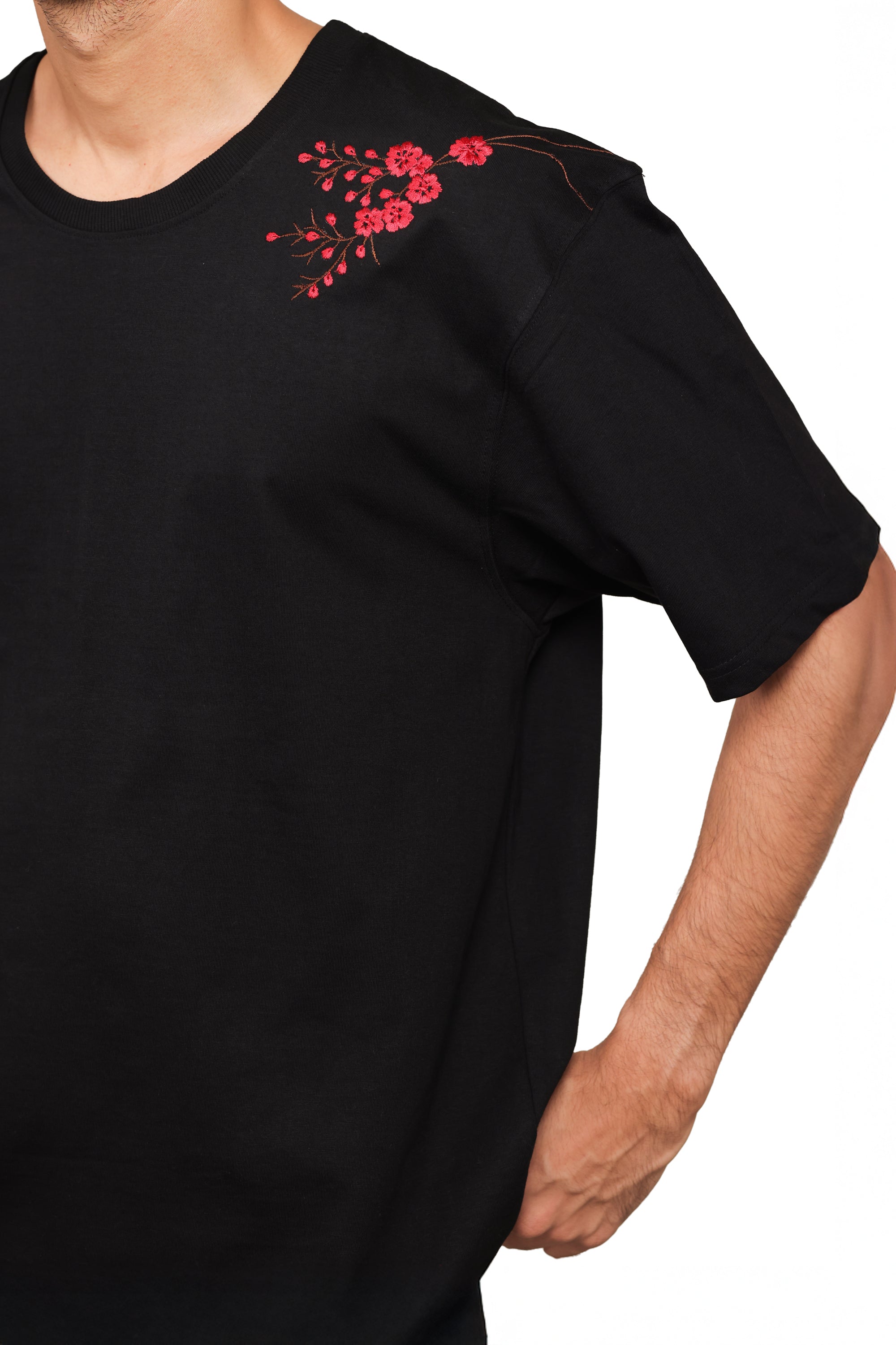 Black t-shirt with red floral embroidery on a white background