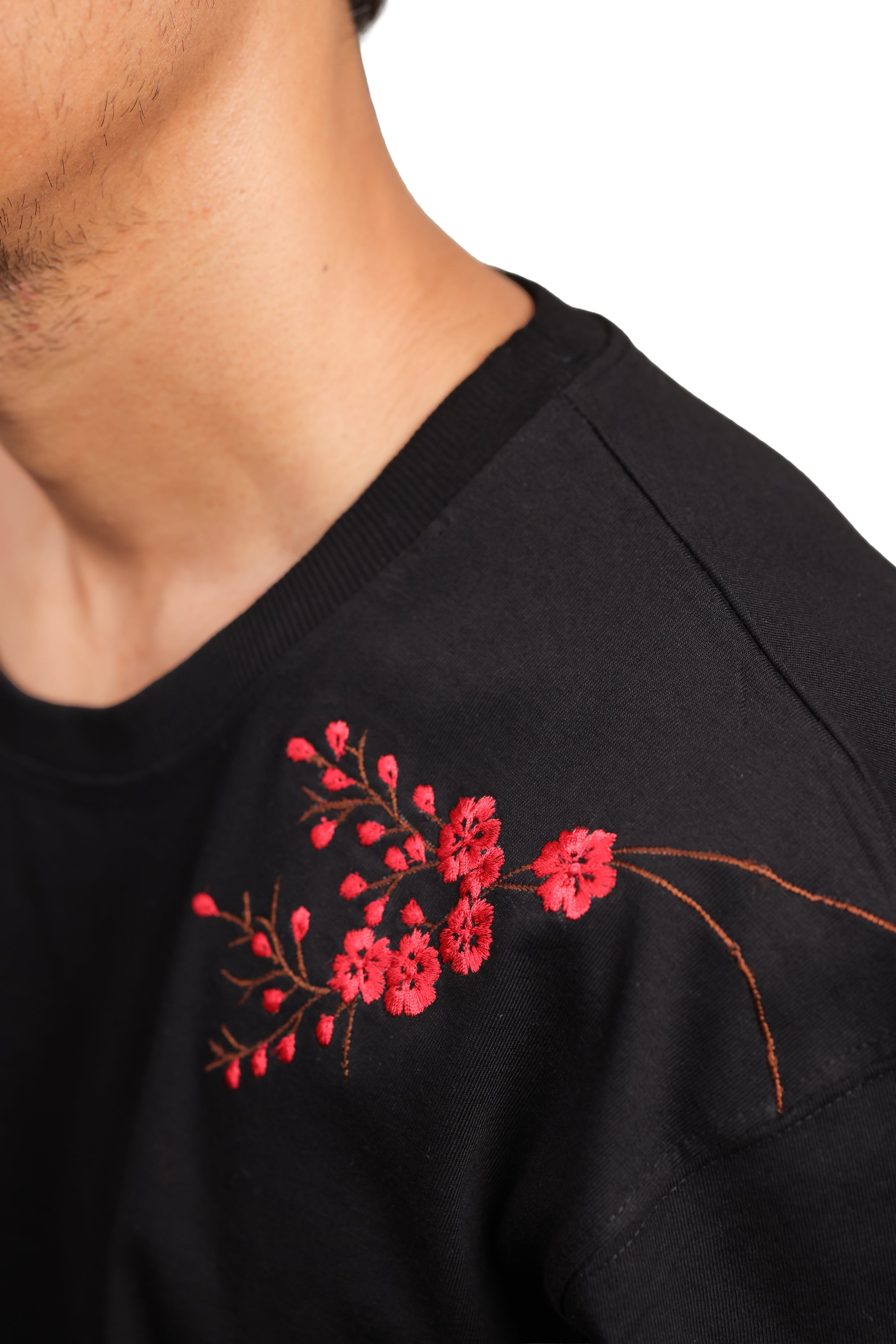 Black shirt with red floral embroidery on a white background
