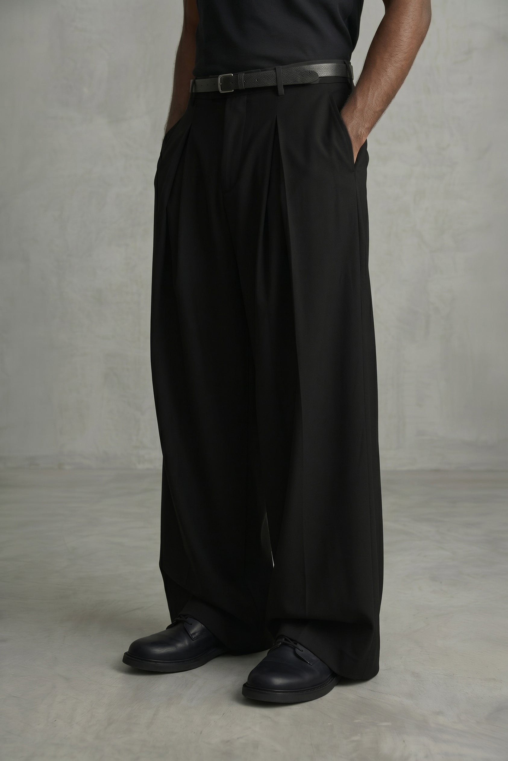 Person wearing black wide-leg pants and black shoes against a plain background