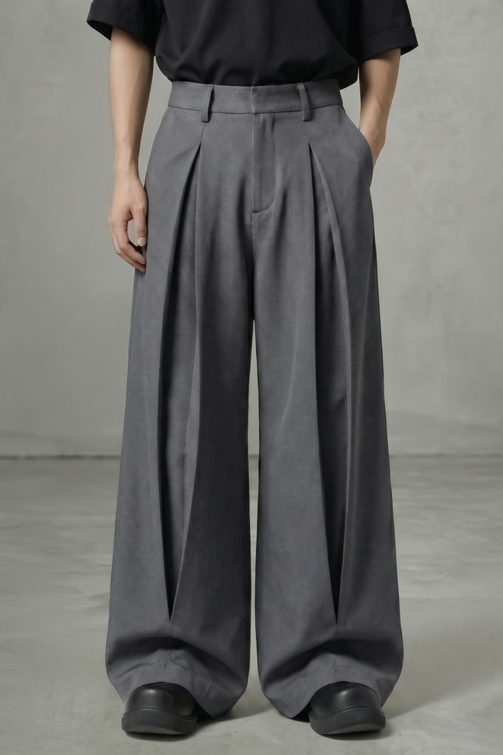 Person wearing gray wide-leg pants and a black top against a neutral background