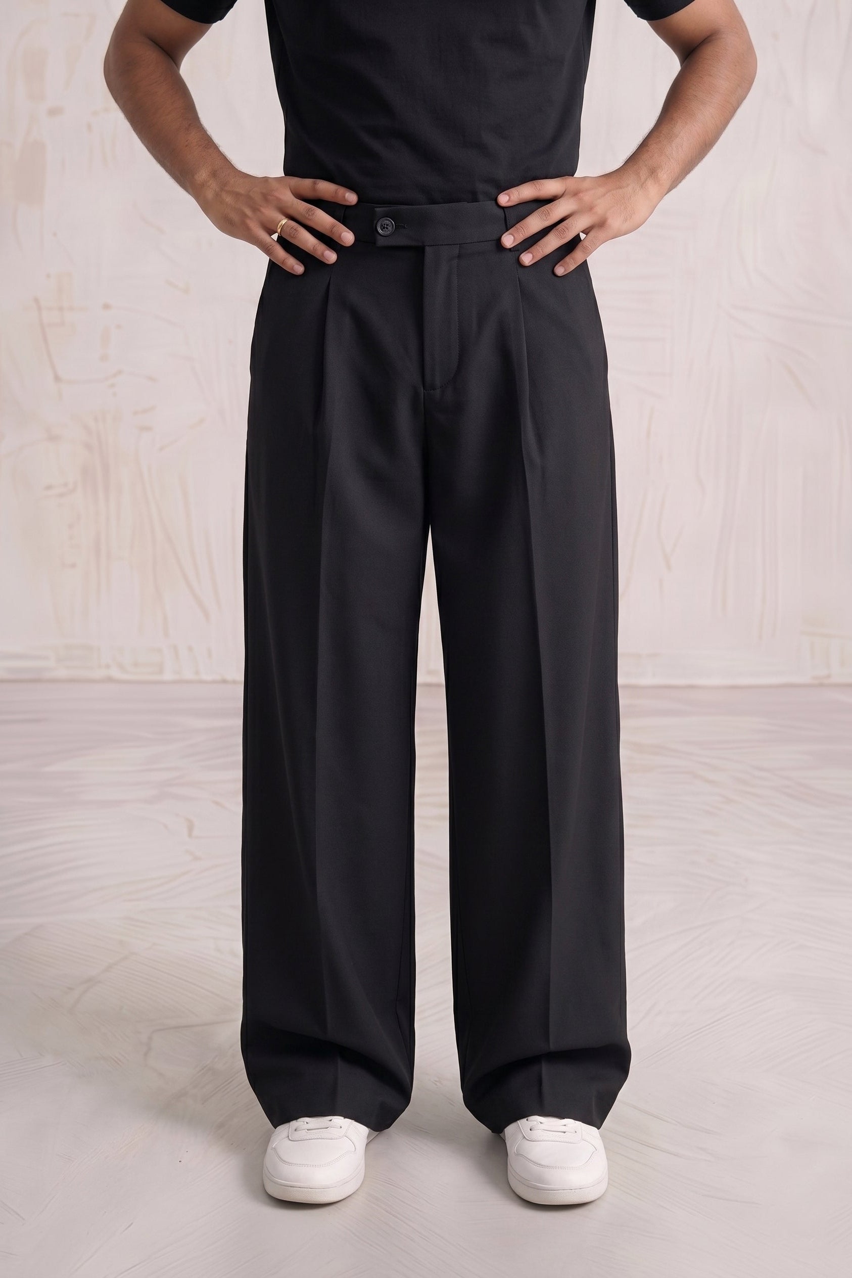 Person wearing black high-waisted pants with a plain background