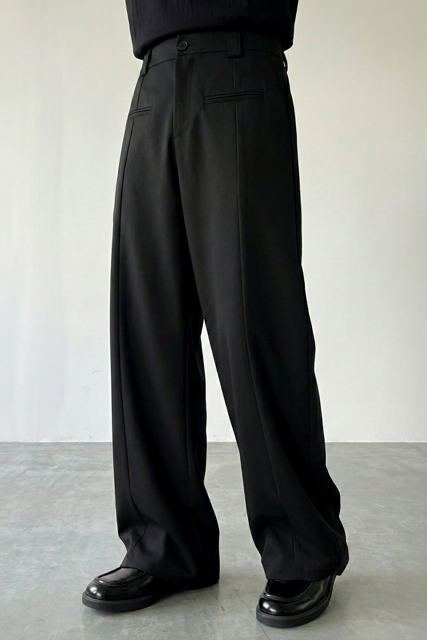 Person wearing black wide-leg pants against a plain background