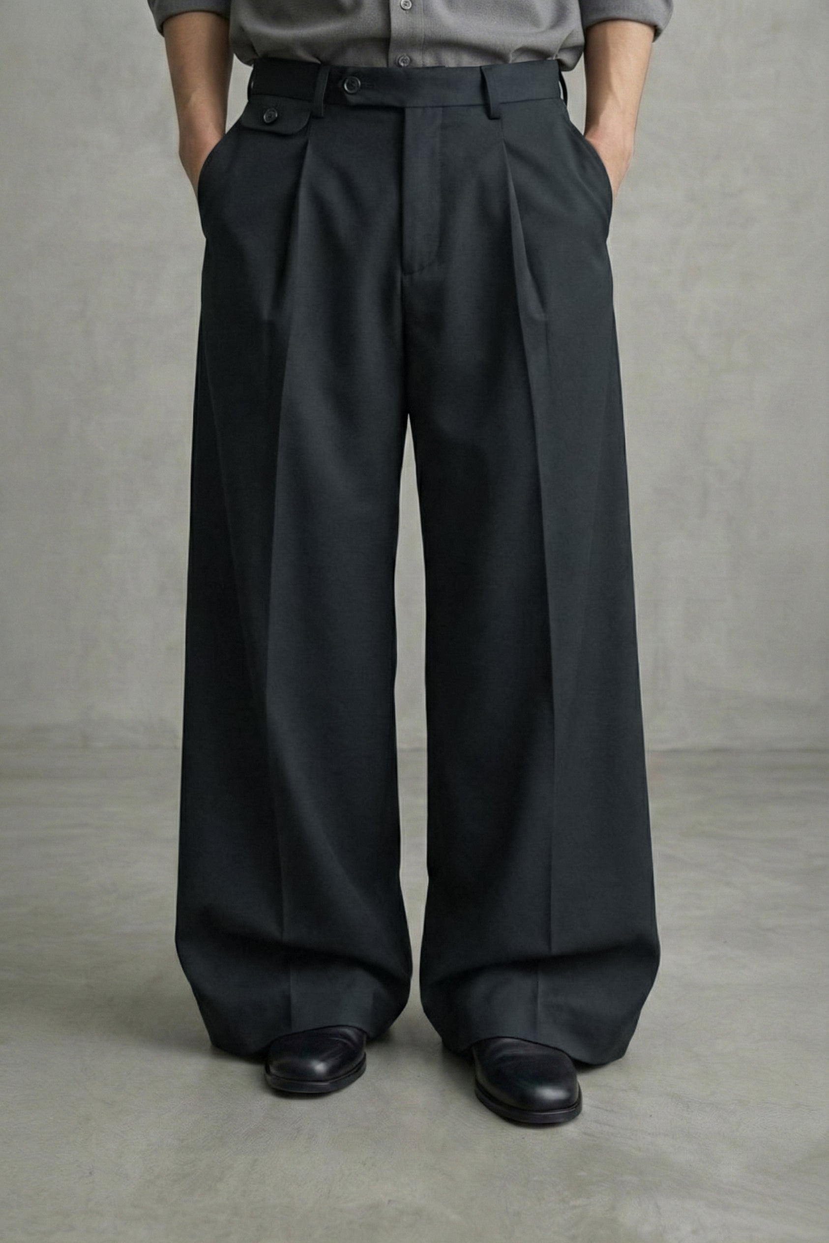 Person wearing black wide-leg pants and a gray shirt against a plain background