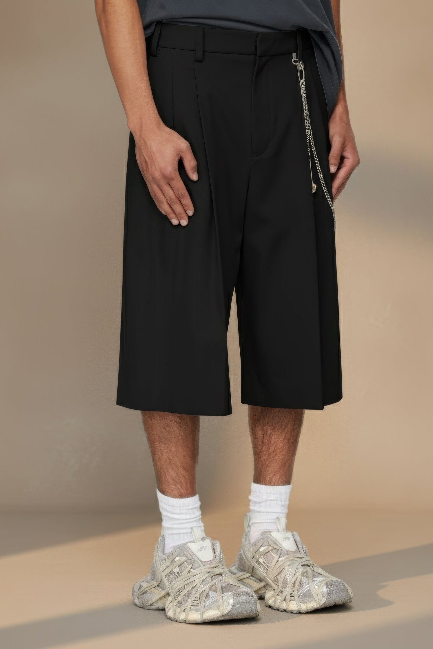 Person wearing black shorts with a zipper on a beige background