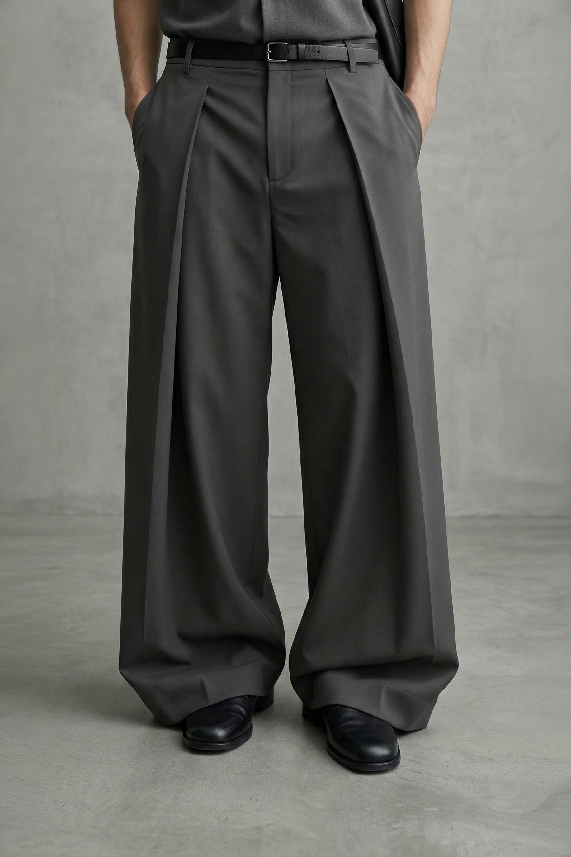 Person wearing dark gray wide-leg pants and black shoes on a plain background