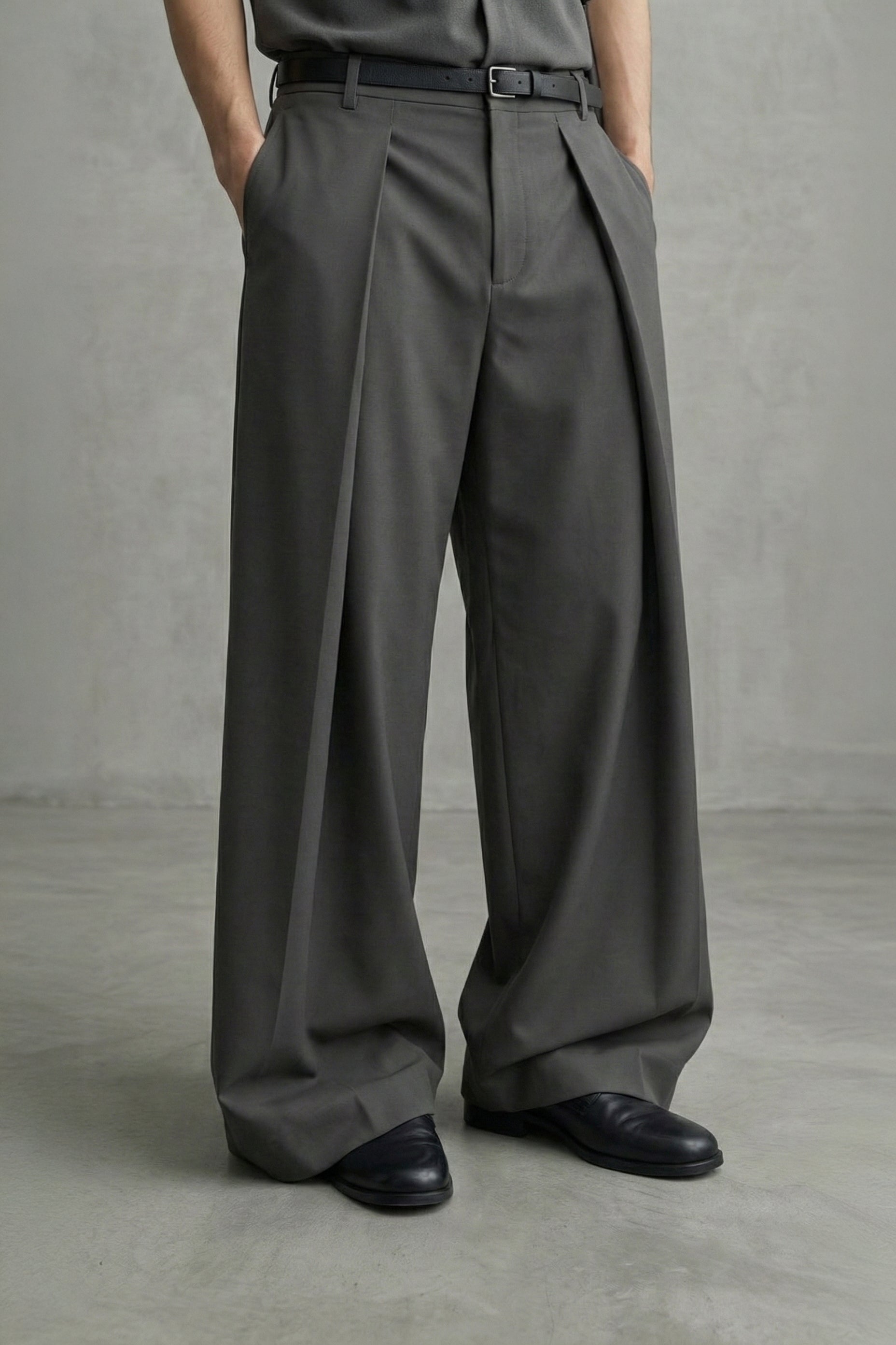 Person wearing gray wide-leg pants and black shoes against a plain background