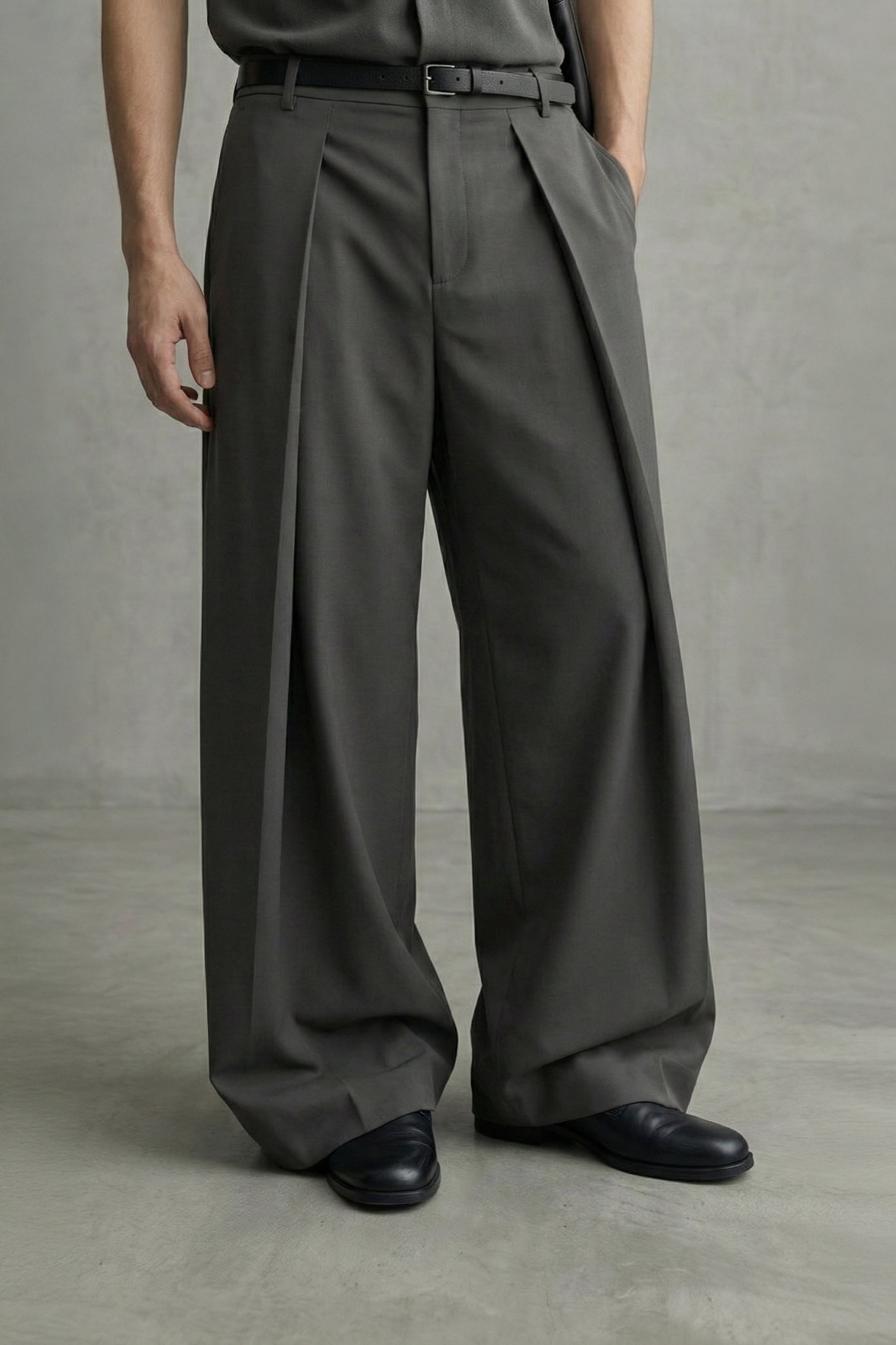 Person wearing dark gray wide-leg pants and black shoes on a plain background