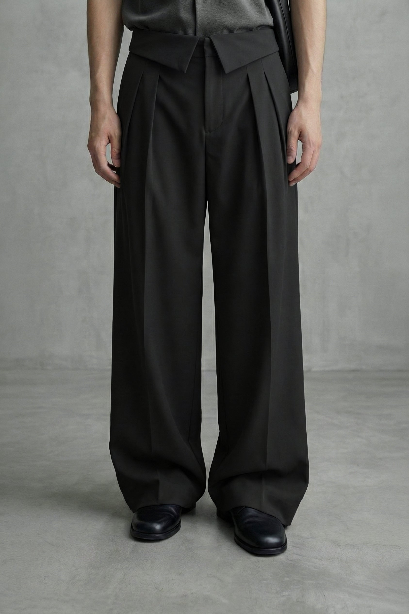 Person wearing black wide-leg pants and black shoes on a gray background