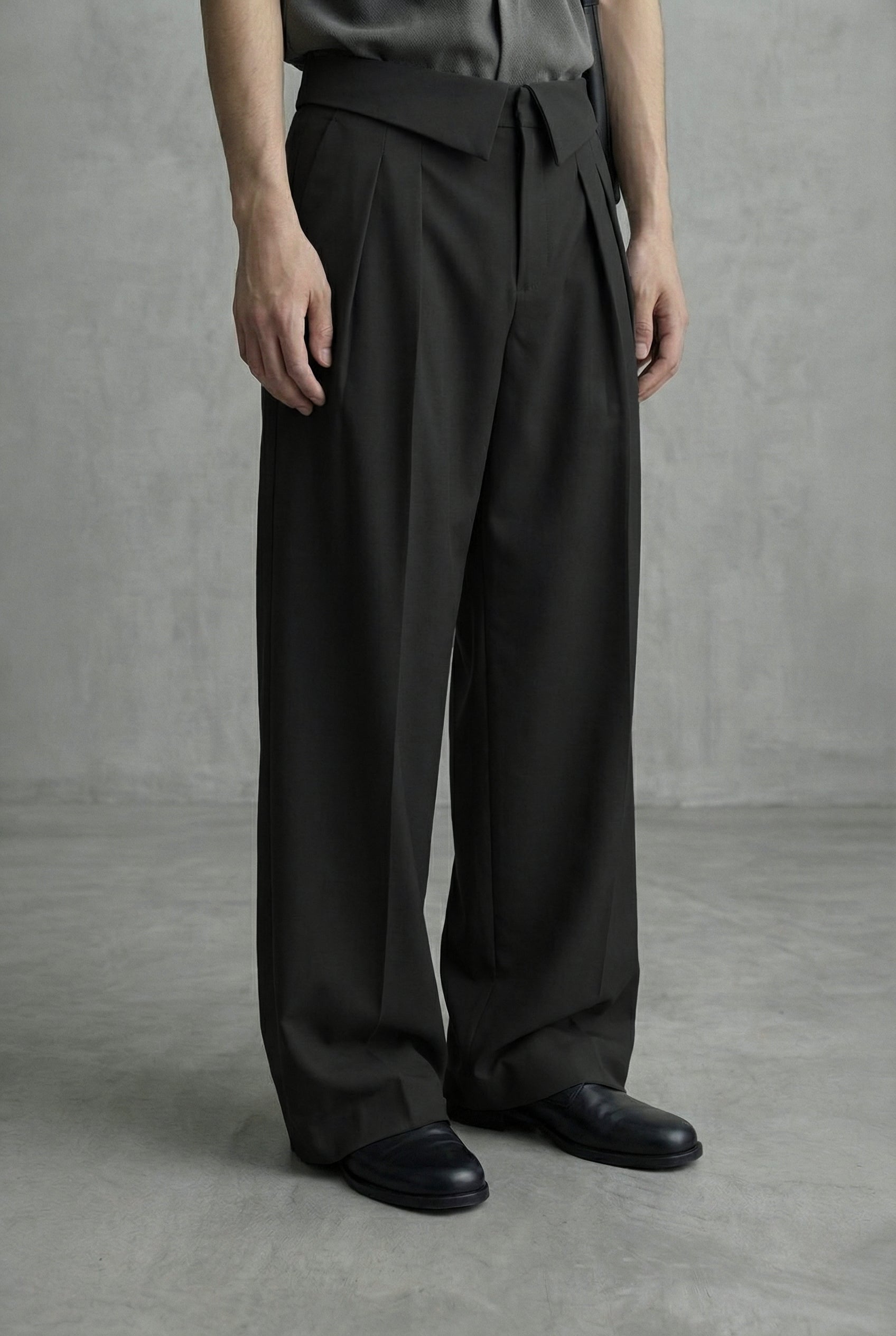 Person wearing black wide-leg pants and black shoes on a gray background