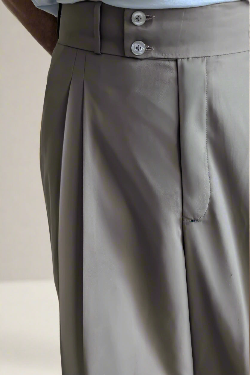 Close-up of beige pleated pants with a plain background