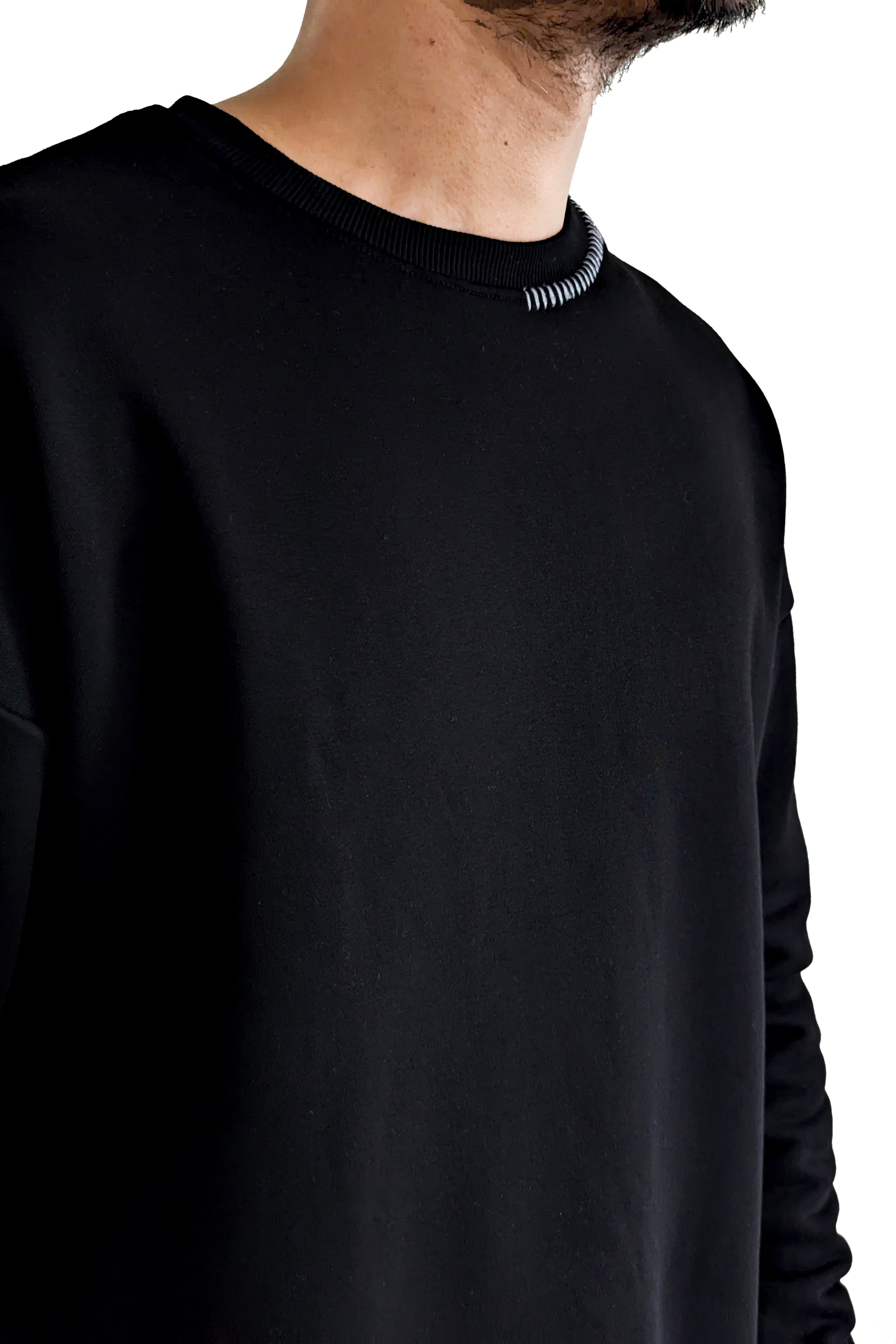 Black long-sleeve shirt worn by a person on a white background