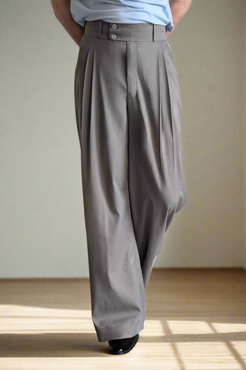 Person wearing gray wide-leg pants with a plain background