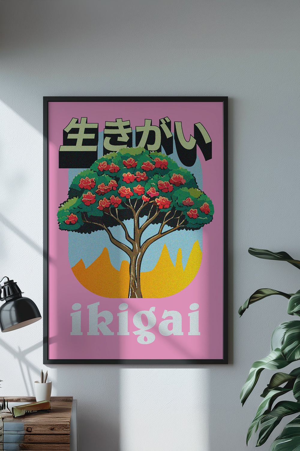Framed poster with a tree and 'ikigai' text on a pink background, hanging on a wall.