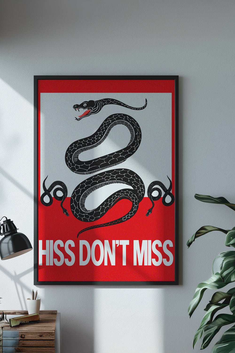Framed poster with a snake design and text 'Hiss Don't Miss' on a wall.