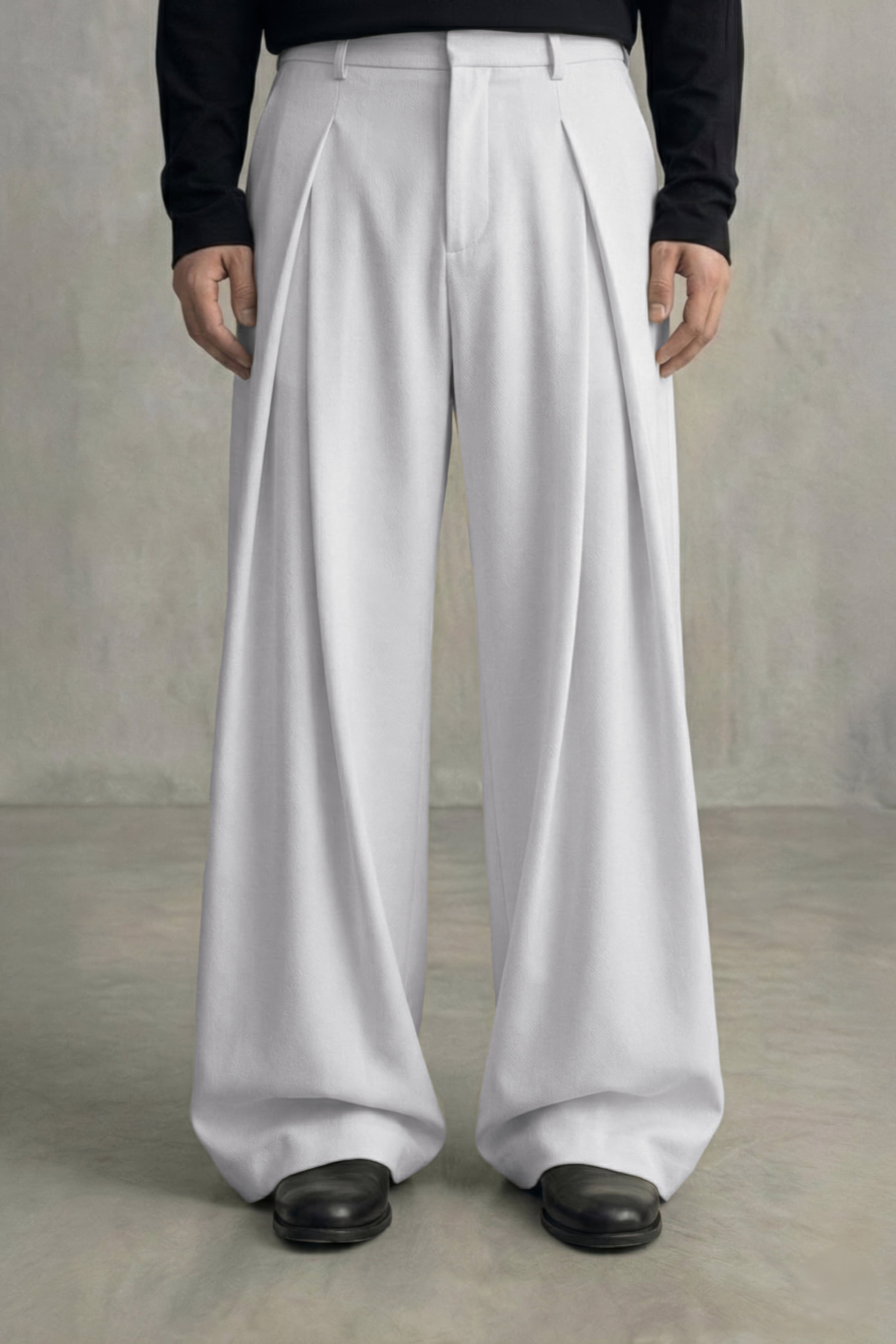 Person wearing white wide-leg pants and black shoes on a plain background