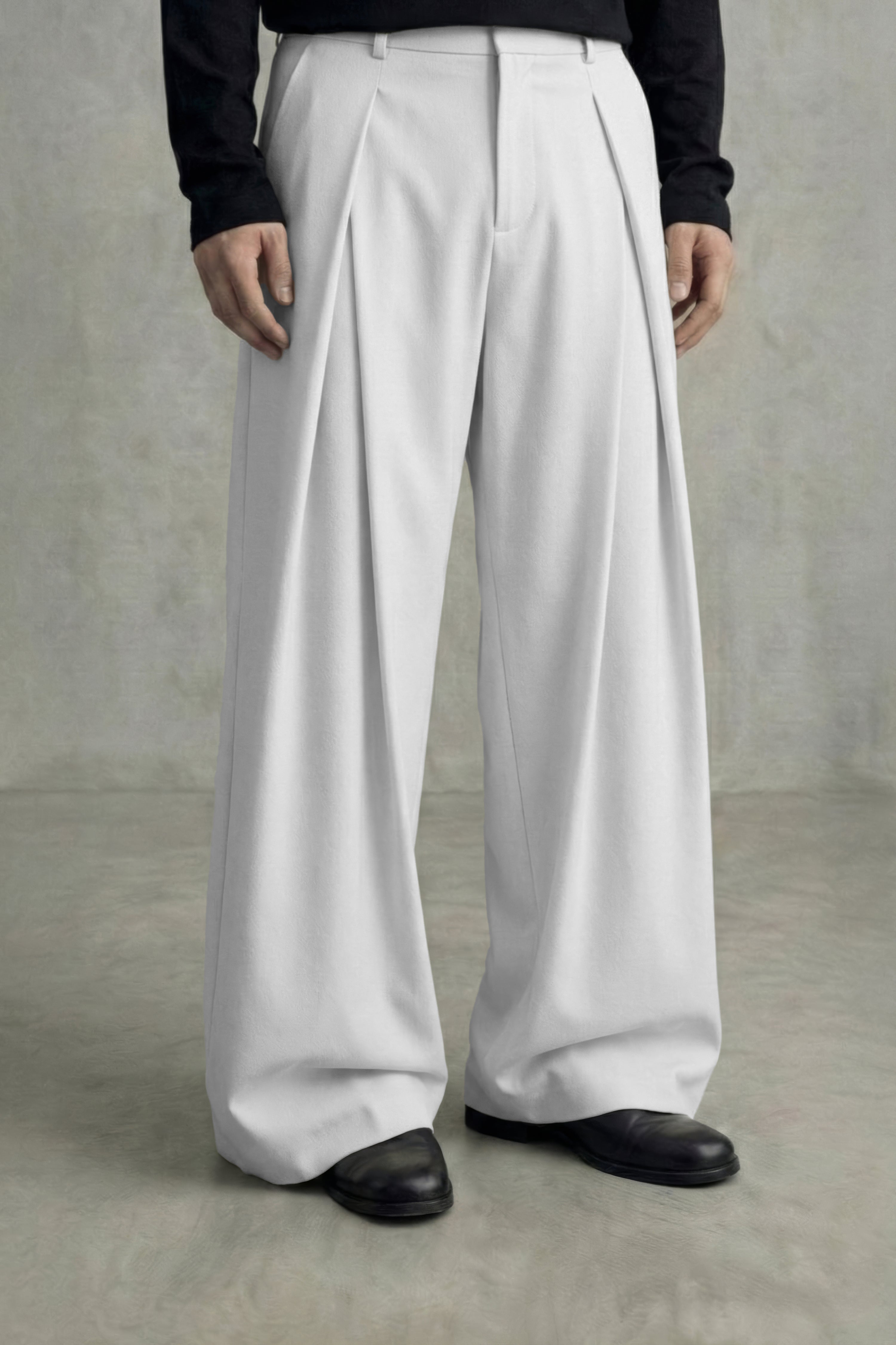 Person wearing white wide-leg pants and black shoes on a plain background