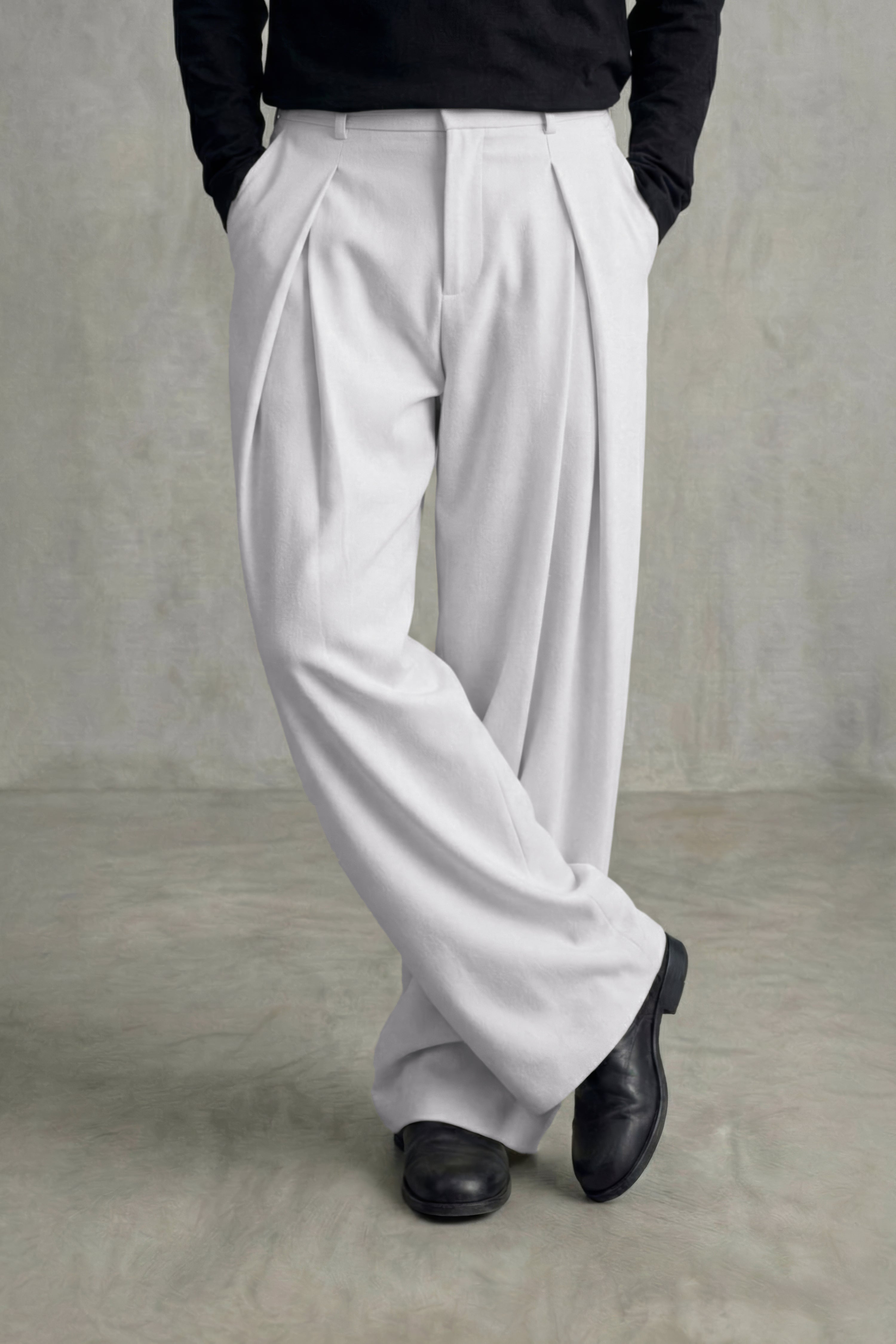 Person wearing white pleated pants and black shoes on a plain background