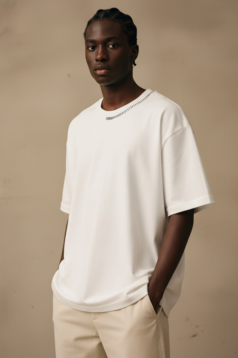 Man wearing a white t-shirt and beige pants against a beige background