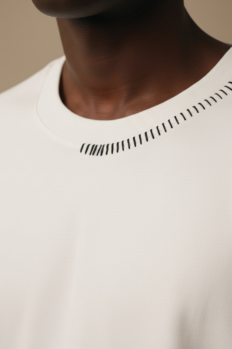 Close-up of a person wearing a white shirt with black geometric patterns on a beige background