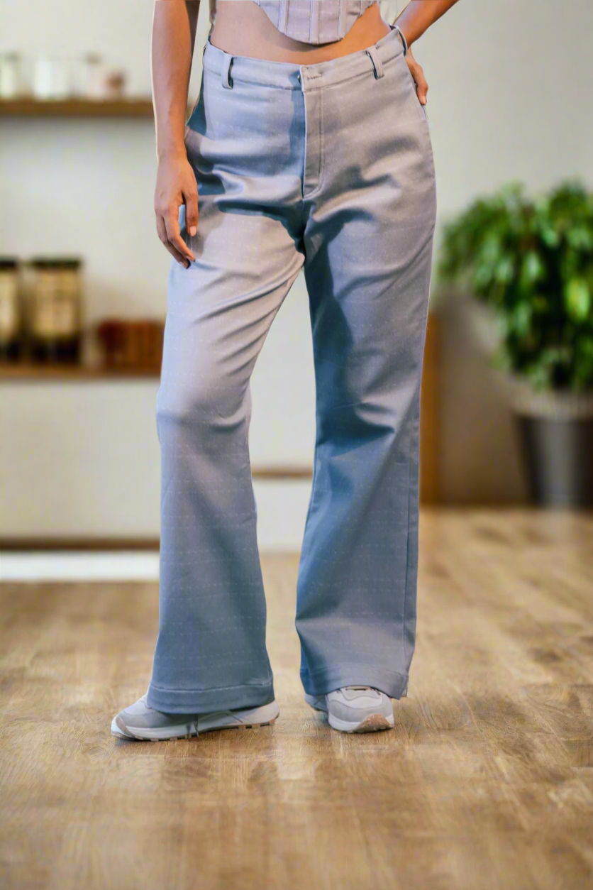 Person wearing light-colored pants standing on a stone floor with a colorful rug and sofa in the background.