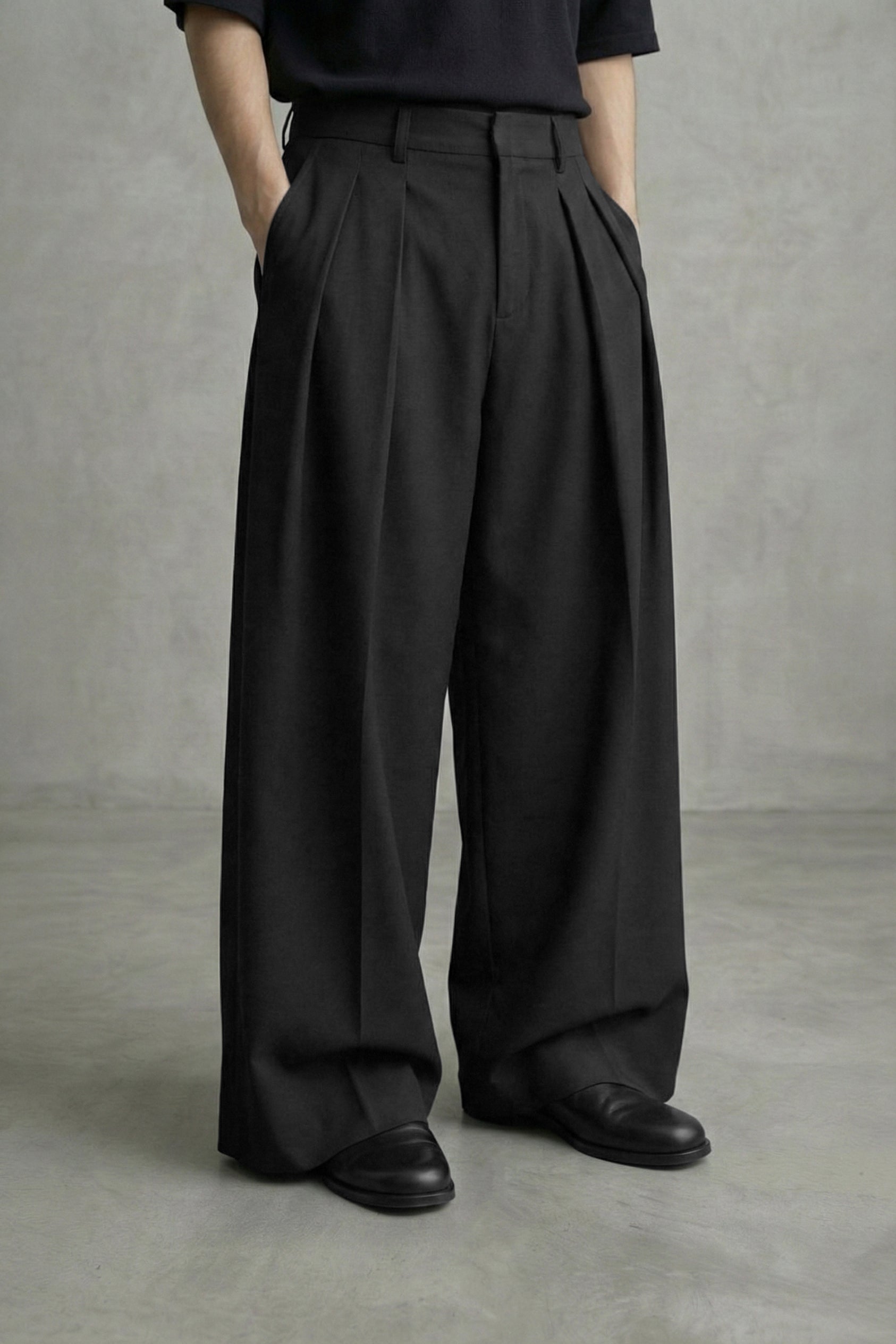 Person wearing black wide-leg pants and black shoes on a plain background