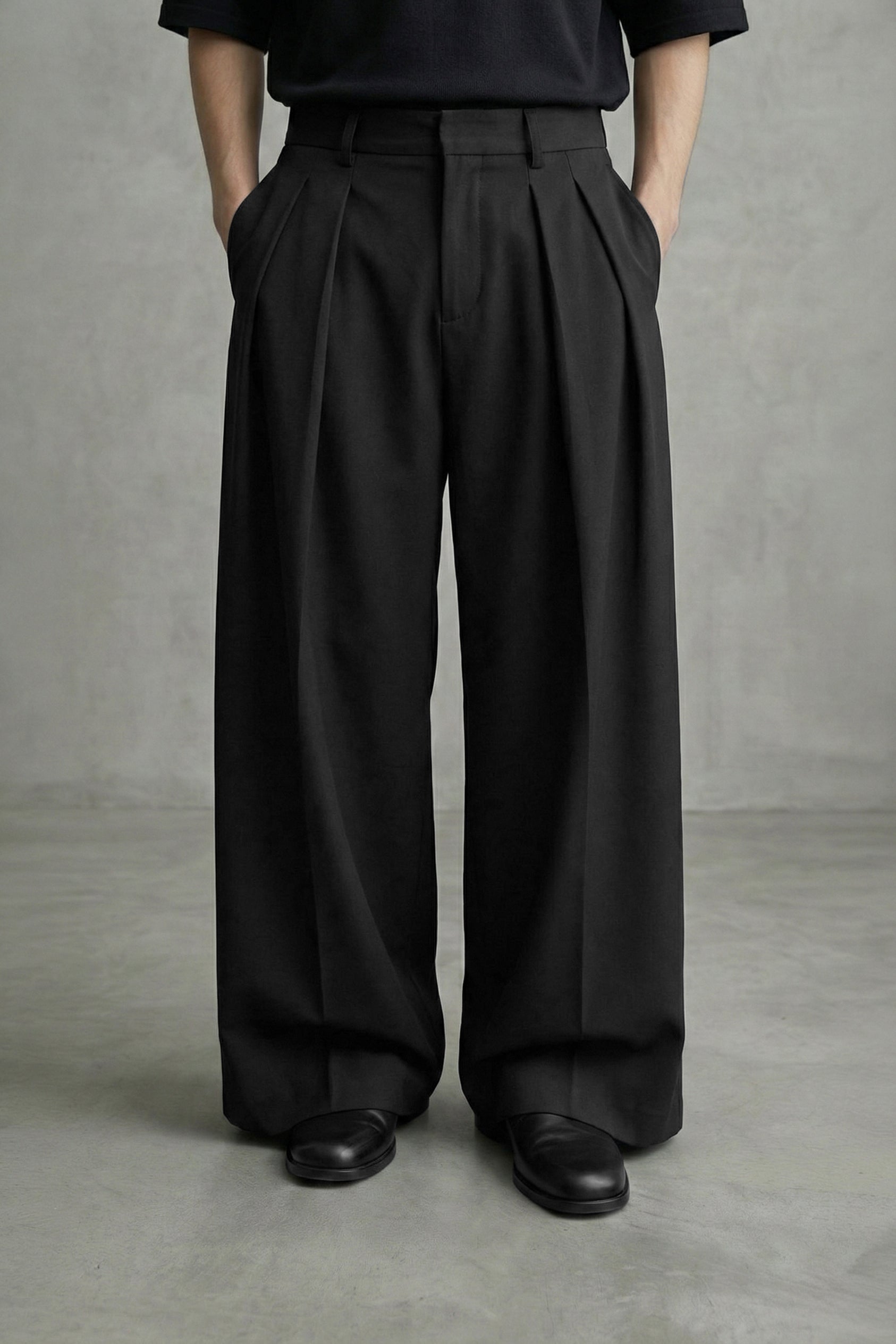 Person wearing black wide-leg pants and black shoes on a gray background