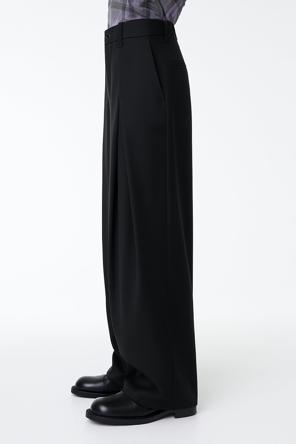 Person wearing black wide-leg pants on a white background