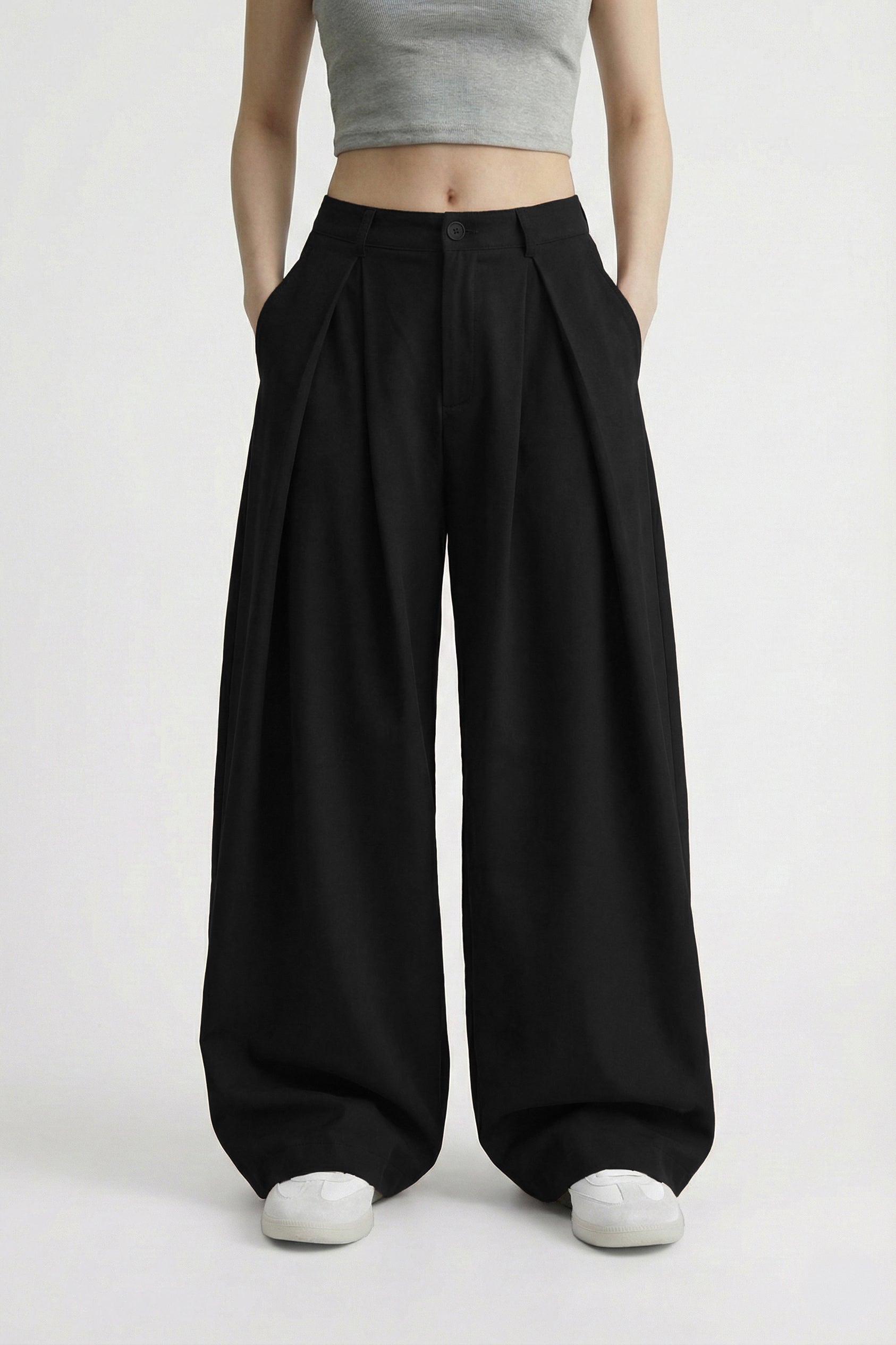 Person wearing black wide-leg pants and a gray crop top on a white background