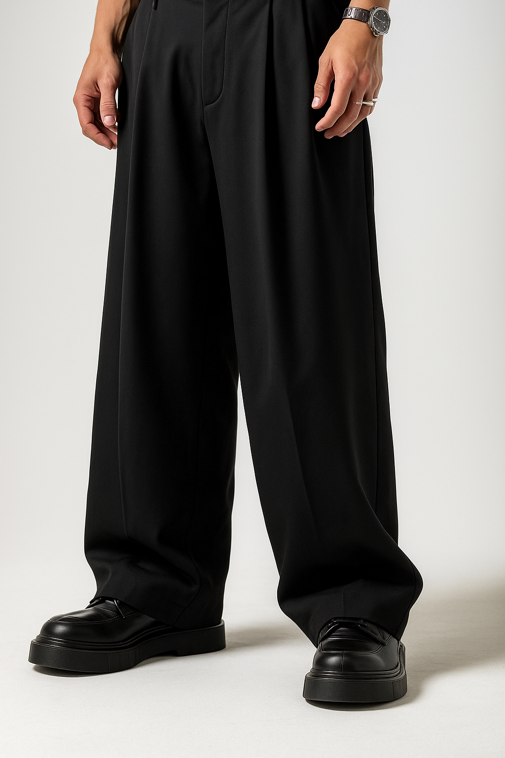 Person wearing black wide-leg pants and black shoes on a white background