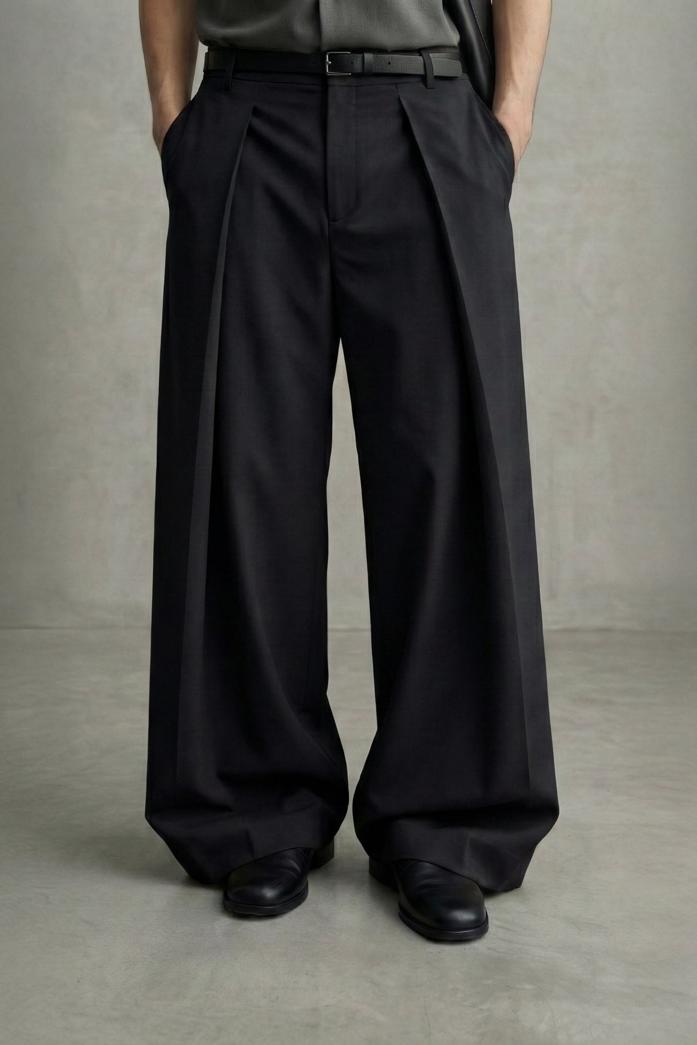 Person wearing black wide-leg pants and black shoes on a plain background