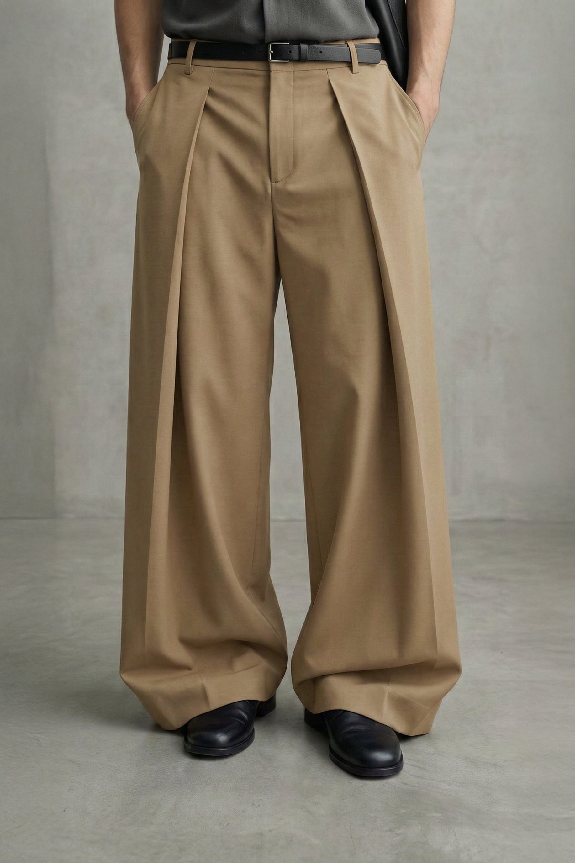 Person wearing beige wide-leg pants and black shoes against a plain background