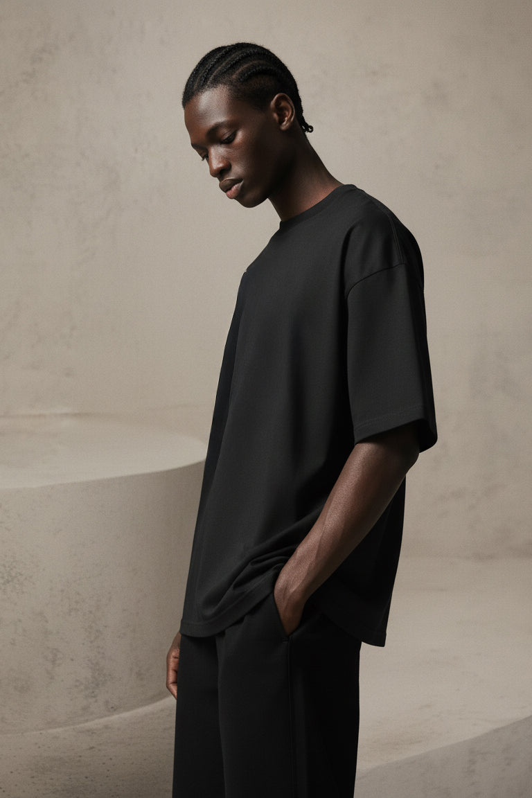 Man wearing a black t-shirt and pants against a beige background