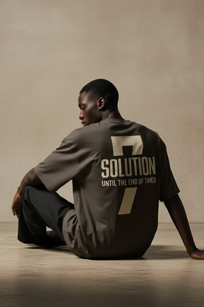 Person wearing a shirt with '7 Solution Until the End of Times' text sitting on the floor.