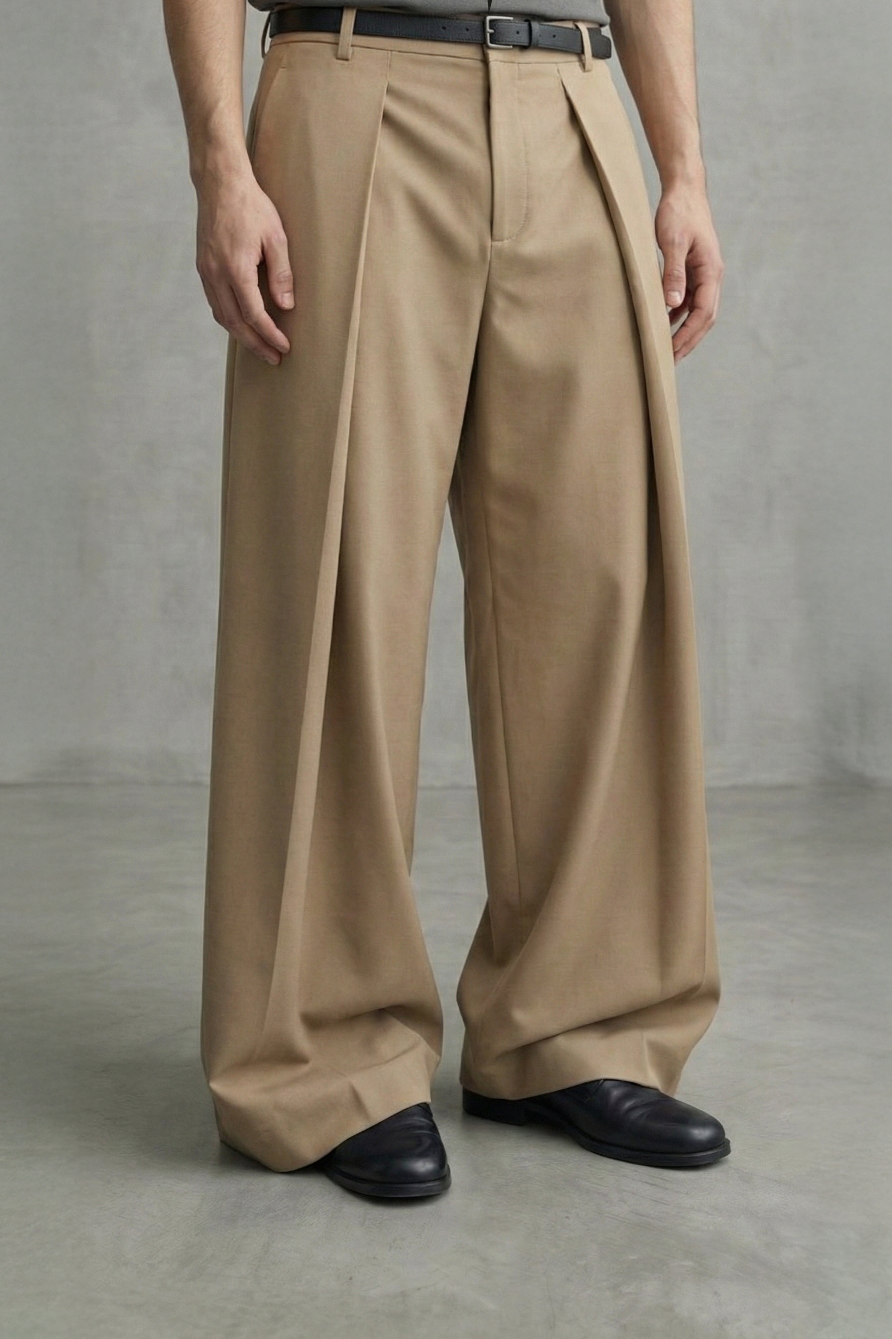 Person wearing beige wide-leg pants and black shoes on a plain background