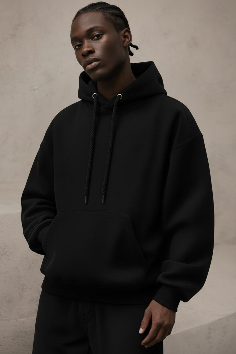 Person wearing a black hoodie against a beige background