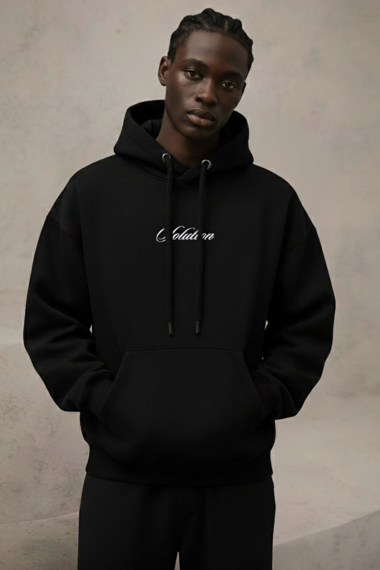 Person wearing a black hoodie with white text on a neutral background